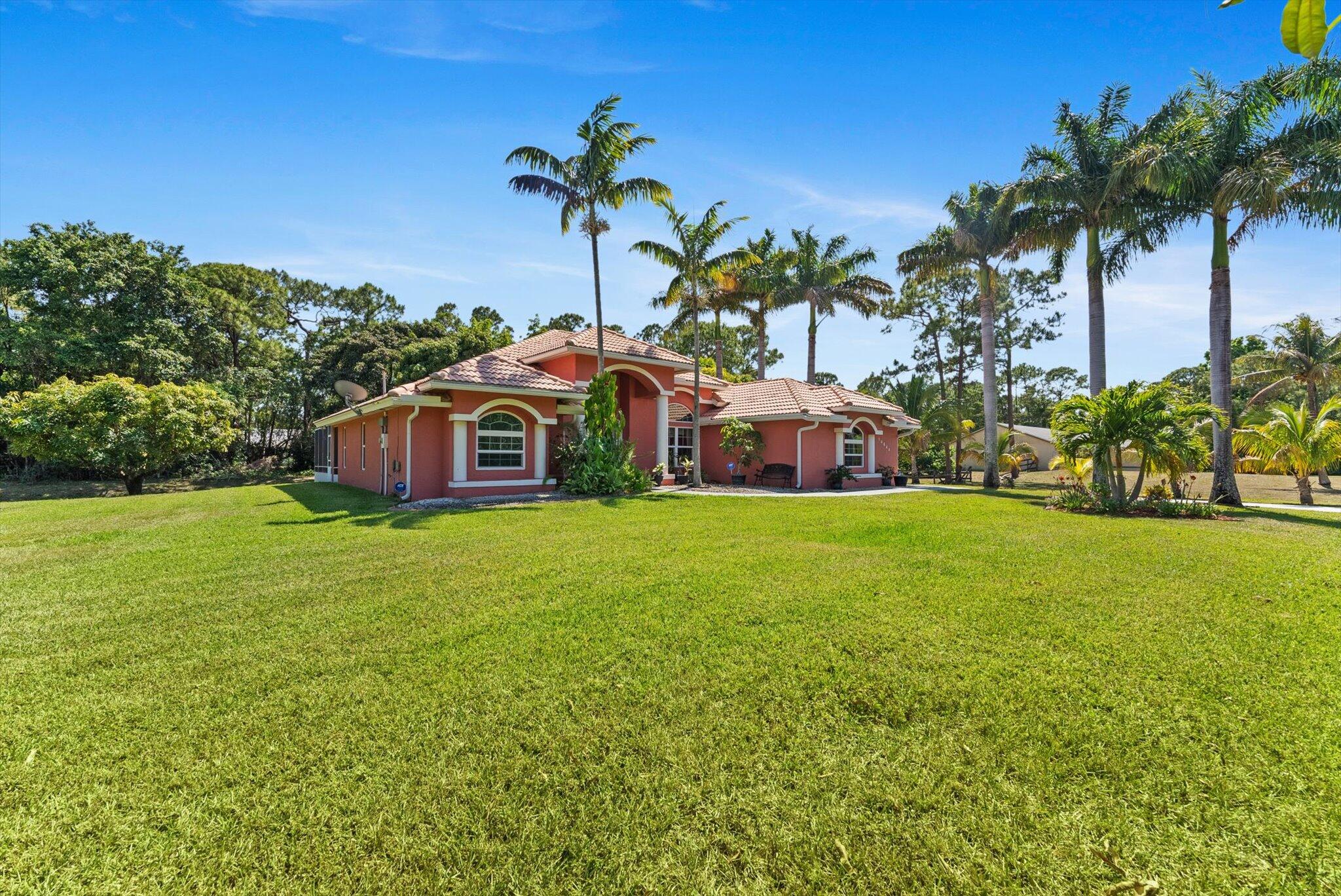 Meticulously maintained 3/2 on 1.19 acres in The Acreage. NO HOA! Original owner, move-in ready. Screened patio overlooks a private backyard with mature fruit trees. Roof & HVAC well maintained, whole-home water filtration, and a massive concrete driveway accommodating 10+ vehicles perfect for boats, RVs & trailers. Convenient to shopping & dining.