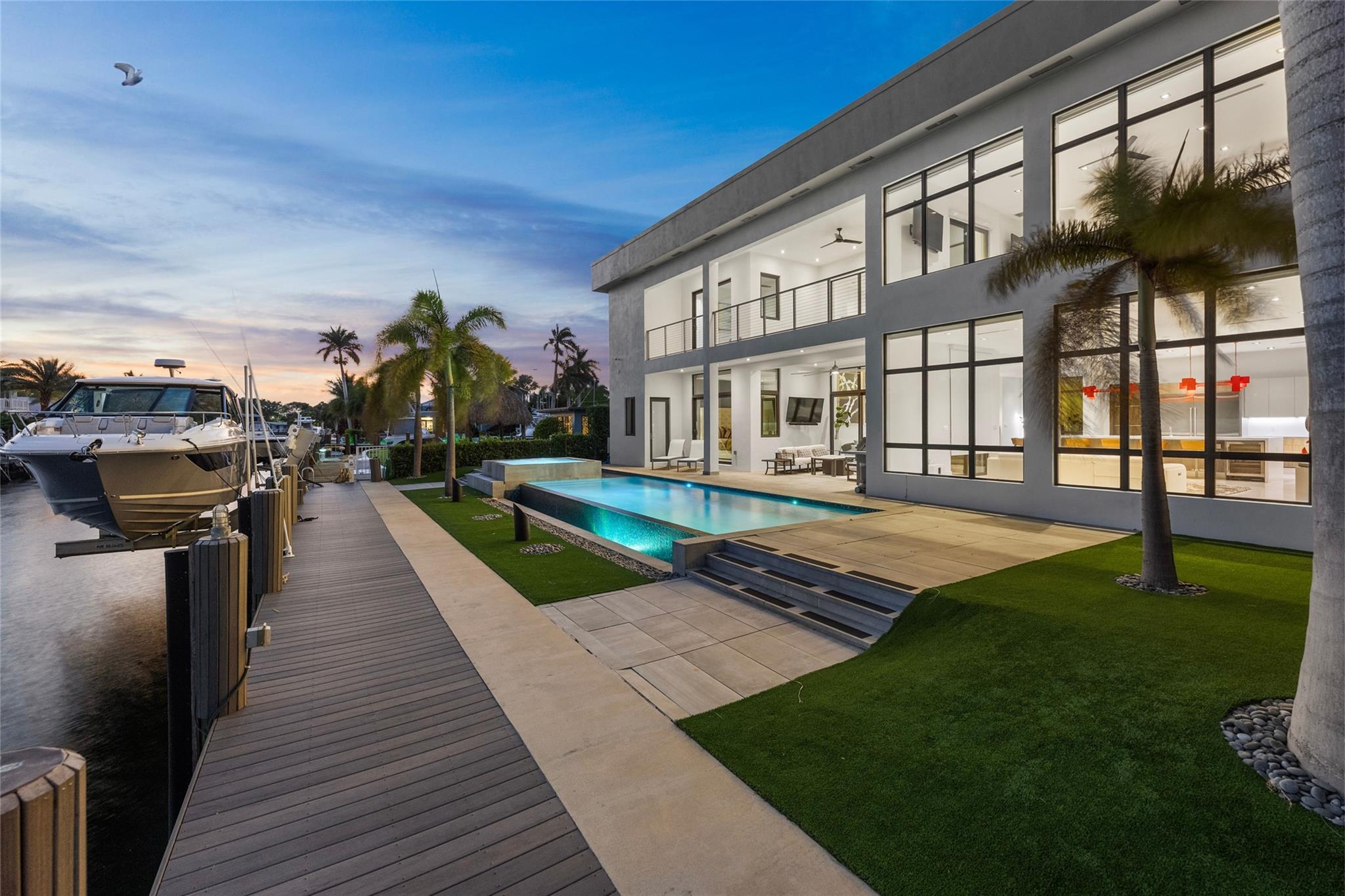 Experience unparalleled luxury just moments from the open ocean! This modern estate offers 80’ of prime waterfront with no fixed bridges, ensuring convenient access to the Hillsboro Inlet, Lake Boca & the Boca Inlet. A custom pivot door welcomes you into soaring ceilings and an open-concept layout that flows effortlessly into your outdoor oasis, featuring a resort-style infinity pool, spa & summer kitchen. The chef’s kitchen is highlighted by sleek Scavolini Italian cabinetry, premium Wolf & Miele appliances, and a large 13’ island with built-in wine fridge. Enjoy your morning coffee from the 2nd floor balcony right off your large primary suite. This is more than a home—it’s a lifestyle reserved for the most discerning buyer! Other notable features include 20,000 lb boat lift and elevator.