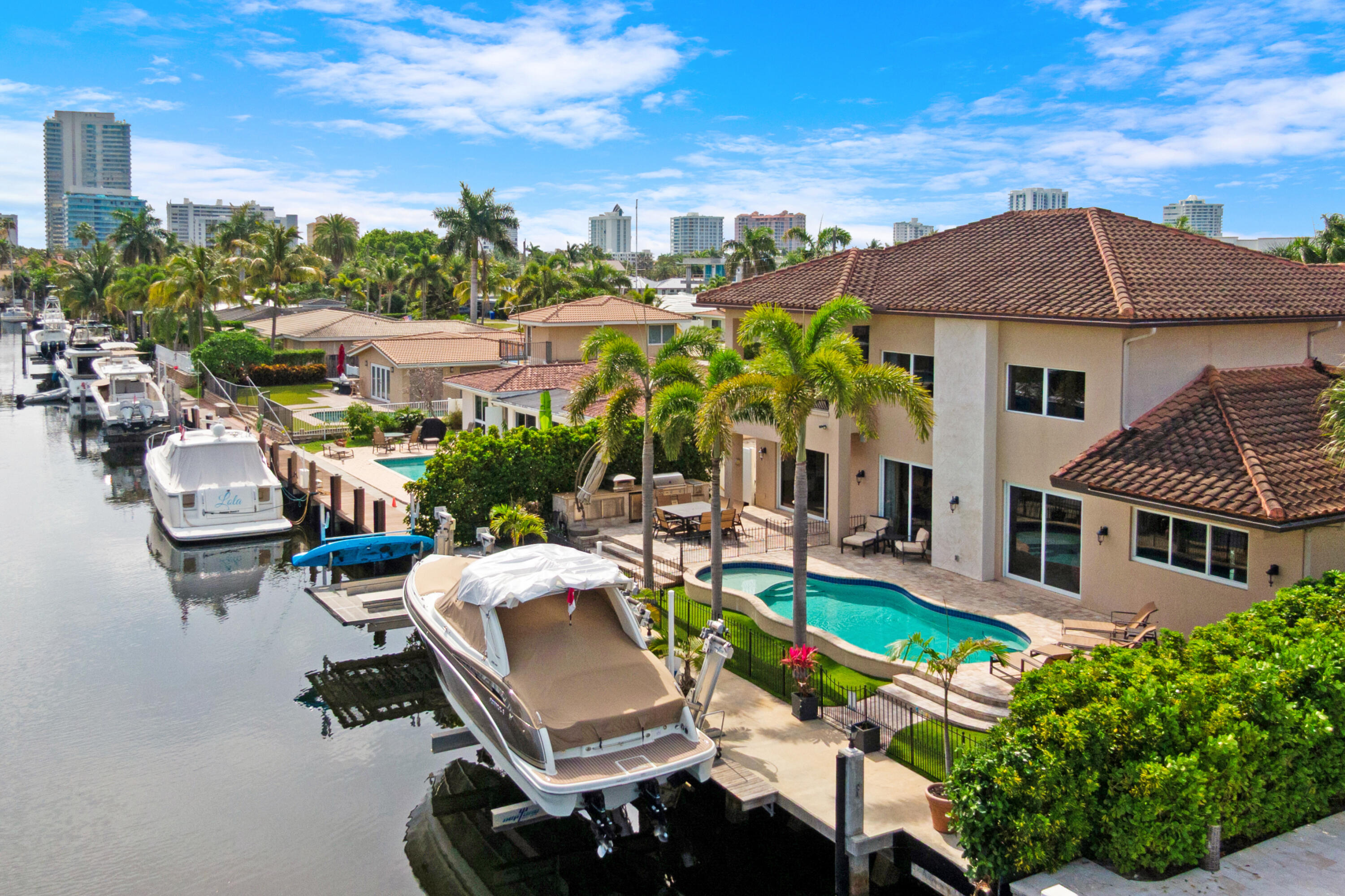 Experience a luxury waterfront estate in Pompano Beach featuring 75 feet of waterfrontage, no fixed bridges, a private dock with boat lift, resort-style pool and spa, and exceptional indoor-outdoor living designed for the ultimate South Florida boating lifestyle. Perfectly positioned on a prime waterfront lot, this 3 bedroom, 4 bathroom residence offers easy ocean access, making it ideal for yacht owners and boating enthusiasts. The private dock accommodates multiple vessels and includes a 22,000 lb boat lift and dedicated jet ski lifts, while wide water views create a stunning backdrop throughout the property. Behind impressive Mediterranean-inspired architecture and lush tropical landscaping, the home welcomes you with a grand double-height foyer, dramatic staircase, soaring ceilings,  and expansive open-concept living spaces filled with natural light. Elegant marble flooring, custom millwork, statement columns, recessed lighting, and designer fixtures elevate the interior throughout. At the center of the home, the chef's kitchen features an oversized island with waterfall-style granite countertops, premium stainless steel appliances, double wall ovens, gas cooktop, built-in wine fridge, custom cabinetry, designer backsplash detailing, and breakfast bar seating, all flowing seamlessly into the formal and informal dining spaces designed for entertaining. The home also includes a custom built-in office/workstation area and spacious loft retreat with a covered balcony overlooking the water and pool area. The luxurious primary suite features tray ceilings, rich wood flooring, and a spa-inspired bathroom with freestanding soaking tub, dual vanities, and oversized windows. Step outside to a private resort-style waterfront retreat featuring a gas-heated saltwater pool and spa, expansive covered living areas, multiple lounging spaces, outdoor shower, and a fully equipped summer kitchen with premium Lynx grill and built-in outdoor cooking station. Oversized sliding glass doors create seamless indoor-outdoor flow, maximizing the waterfront lifestyle. Additional highlights include a climate-controlled 2-car garage, central vacuum system, air purification system, circular paver driveway with guest parking, professionally landscaped grounds, mature palms, manicured hedging, and a second-floor covered balcony with panoramic water views. Pompano Beach is one of South Florida's fastest-growing coastal communities, offering an elevated blend of Waterfront lifestyle, convenience, and long-term investment appeal. The revitalized beachfront offers world-class restaurants and luxury destinations including The W, Ritz-Carlton, and Waldorf Astoria. Enjoy the Pompano Beach lifestyle with an abundance of rooftop lounges, casual oceanfront dining, the iconic fishing pier, and new waterfront parks designed for an active, outdoor lifestyle. Downtown continues to evolve with the completion of the new City Hall and expanded civic spaces, while walkable neighborhoods and the Circuit electric rideshare make getting around easy and efficient. With quick access to intracoastal waterways and ocean access just minutes away, Pompano Beach is a boater's dream community. Local pickleball courts, neighborhood parks, and multiple championship golf courses throughout the area are the cherry on top. For travelers and commuters, you'll have easy access to US-1 and I-95. FLL Int'l Airport is 20 minutes away, Miami Int'l Airport is 45 minutes away, and Palm Beach International Airport is 40 minutes away.