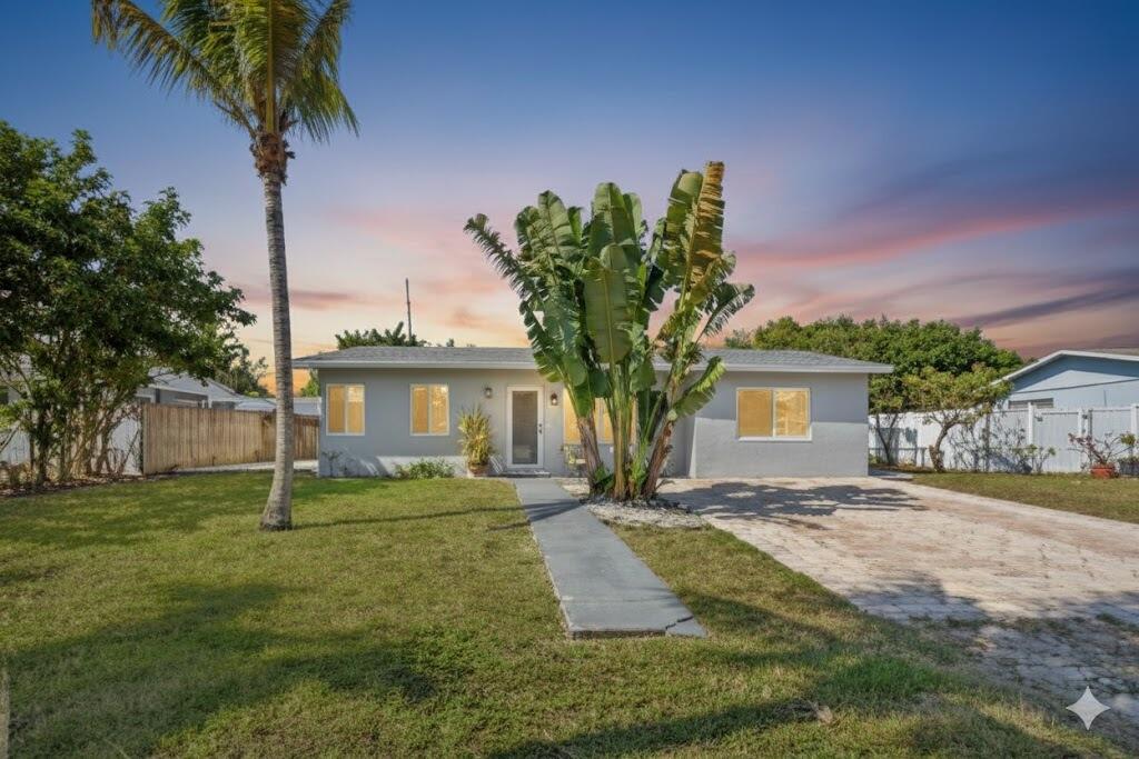 INVESTOR FRIENDLY • NO HOA • BRAND NEW ROOF!! Welcome to this beautifully maintained single family, renovated, home offering flexibility, modern upgrades. The main home features 2 bedrooms and 1 bathroom, plus a separate private bonus suite complete with its own side entrance and full bathroom. Ideal for multigenerational living, guests or a private home office, this layout offers incredible versatility. The extended driveway accommodates up to 6 vehicles. From the moment you arrive, the tropical curb appeal makes a lasting impression. A striking bird of paradise and traveler's palm frame the light gray exterior, while the BRAND NEW ROOF and full impact windows and doors provide both style and peace of mind. The brick paved driveway, mature palms, and concrete walkway leading to a frosted glass front door complete the welcoming exterior.  Inside, the airy open concept layout is filled with natural light and enhanced by weathered wood-look plank flooring and soft periwinkle blue walls. The spacious living area flows seamlessly into the updated kitchen, creating an inviting and functional space for everyday living and entertaining.  The kitchen showcases light gray shaker cabinetry, stainless steel appliances, crisp white countertops, and a marble-inspired subway tile backsplash for a timeless yet contemporary feel. Teardrop pendant lights suspended from a rich wood beam add warmth and character above the breakfast bar, tying the space together beautifully.  Just off the kitchen, a flexible adjoining room offers endless possibilities, perfect for a home office, fitness space, or formal dining area. Beyond that, a sun-drenched bonus room wrapped in expansive windows provides peaceful views of the lush greenery outside. Grey toned wood plank flooring and a distinctive plank style ceiling add architectural interest and enhance the sense of openness, while a wide cased opening maintains the open-concept flow with subtle definition.  Both bedrooms are generously sized with ceiling fans, multiple windows, and ample closet space, including mirrored closet doors in the secondary bedroom. The updated bathroom continues the home's modern aesthetic with a gray shaker vanity, white countertop, chrome fixtures, and marble-patterned tile extending into the walk-in shower, finished with herringbone tile flooring and sleek hardware.  The private bonus suite mirrors the home's cohesive style with periwinkle blue walls and wood look flooring. Bright and airy, it features a modern ceiling fan, large window, private side entrance with built-in pet flap, and a wall mounted mini split A/C for individualized comfort. There is a small kitchen area with a granite style countertop, stainless undermount sink, brushed nickel faucet, white shaker cabinetry, and open shelving. The adjoining full bathroom is finished with large format marble tile, a light gray vanity, modern brushed fixtures, and a walk in shower with a rain showerhead and herringbone mosaic flooring.  Step outside to the expansive screened in porch, currently outfitted with a washer and dryer, storage shelving, and seating areas, offering flexibility as a utility space, outdoor lounge, or entertainment area. The fully fenced backyard provides privacy with mature trees, wood and chain-link fencing, and plenty of room to customize, including space to add a pool. A tiled pathway and private side access enhance the functionality and privacy of the bonus suite.  Cresthaven is a well-established neighborhood in northeastern Pompano Beach, just about a mile west of the Atlantic Ocean. Originally developed in the 1950s as a winter retreat, it has grown into a vibrant community featuring a mix of mid-century bungalows and expanded ranch-style homes, appealing to first-time buyers, growing families, and those seeking long-term value. Its tree-lined streets and welcoming atmosphere create a true sense of neighborhood charm. Residents enjoy convenient access to major roads like US-1 and Interstate-95, making downtown Fort Lauderdale, beaches, and other South Florida hubs easily reachable. The area offers an array of shopping and dining options, including Publix, Whole Foods Market, and local favorites like The Hen and the Hog, as well as parks, playgrounds, and recreational facilities such as Cresthaven Park and the nearby Pompano Beach Municipal Golf Course. With its combination of convenient location, parks, and close proximity to the coast, Cresthaven offers an ideal balance of relaxed beach-side living and everyday practicality.