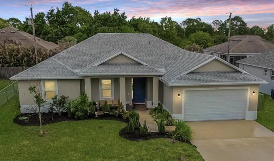 Welcome to this beautifully maintained single-story home in the heart of Port St. Lucie, offering 2,142 square feet of comfortable living space with 4 bedrooms, 2.5 bathrooms, and no HOA or restrictions. Designed for both everyday living and entertaining, this home features an inviting entrance foyer, a front door with natural daylight, high ceilings, and stylish plank-style wood tile flooring throughout.  The spacious open-concept layout seamlessly connects the dining and living areas to a well-appointed kitchen featuring a large center island with bar seating, granite countertops, appliances, and abundant cabinet storage. Large impact windows throughout the home provide peace of mind while filling the interior with natural light.   The generous primary suite and secondary bedrooms offer comfort and flexibility for family, guests, or a home office. Step outside and enjoy both the front and back patios. Perfect for entertaining, relaxing, or enjoying Florida's beautiful weather. The fenced backyard provides added privacy and security, with plenty of room to create your dream outdoor oasis, including potential space for a future pool.  Additional highlights include a 2-car attached garage, an extended driveway for extra parking, and a desirable location close to shopping, dining, parks, schools, and major commuter routes. This move-in-ready Port St. Lucie gem combines comfort, functionality, and freedom with no HOA restrictions. Don't miss the opportunity to make it yours! Washer,Dryer and drapes do not convey.