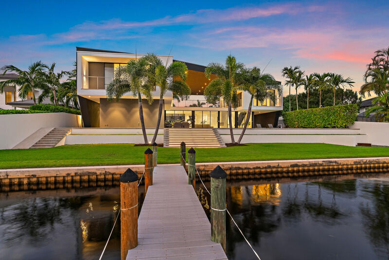 HughesUmbanhowar Architectural Masterpiece on the Loxahatchee River. Featured in Modern Luxury Interiors South Florida and Palm Beach Illustrated. 4 en-suite bedrooms in total/2 half baths featuring a private en-suite guest wing. Privacy and modern elegance combine to make this home one of the finest in Jupiter. Situated on a private 0.6-acre lot, this thoughtfully designed estate offers breathtaking water views and deck access from every room. Abundant natural light accentuates the home's clean architectural lines and outdoor connection. With a striking white and gunmetal palette carried seamlessly throughout the interior and exterior, the architecture itself becomes the home's defining artwork. Offered fully turn-key, the home is furnished with custom pieces by B&B Italia, Luminaire and Design Within Reach. The fully outfitted kitchen is complete with custom walnut cabinetry, a Bertazzoni cooktop, Miele appliances, and a dramatic Wagamama waterfall marble island-creating a truly effortless move-in experience. Spanning 5,099 square feet of harmoniously designed living space, the home features meticulous hardware-free, soft-close cabinetry and concealed appliances that allow the kitchen to blend naturally into the surrounding living and dining spaces. A sophisticated architectural lighting plan by Delta Light, thoughtfully layered with recessed fixtures, enhances the home's modern aesthetic and beautifully highlights its clean, minimalist lines. Complementing this design, sleek circulation grills and linear slot diffusers provide optimal air movement while maintaining the home's refined look. The first floor is finished with terrazzo floors with a modern matte finish, while the second floor transitions to warm, refined wood flooring. The kitchen and living areas, framed by Fleetwood telescoping doors, open seamlessly to a spacious recreational family room, outdoor kitchen, expansive outdoor terrace and a beautifully designed EURO edge salt water pool with built in hot tub, offering an elevated environment for both entertaining and quiet relaxation. The second floor hosts three en-suite bedrooms, each with private balconies, showcasing Resysta deck flooring, and stunning water and estate views. The primary suite features a dual-access wet room-style shower adorned with Robern mirrors. In addition, a separate guest wing across the covered terrace includes its own en-suite flex space, complete with a custom Murphy bed and its own spectacular balcony views. Elevating this extraordinary property is a private dock with a 12,000-pound boat lift (including Jet Ski), protective seawall, and easy ocean access-ideal for enjoying the very best of Jupiter's waterfront lifestyle. With its refined design and uncompromising attention to detail, this exclusive home is the epitome of luxury living in South Florida.