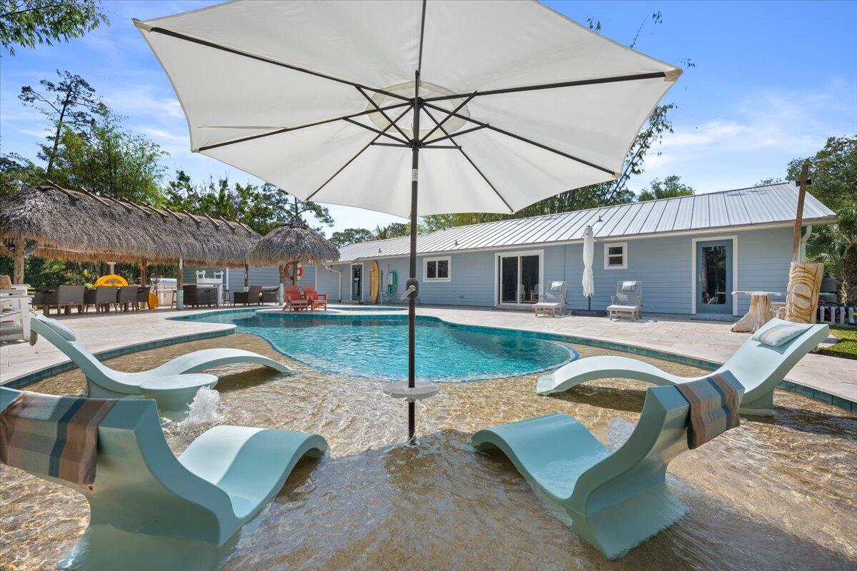 Welcome to this stunning Jupiter Farms home, where every day feels like a vacation! Set on a fully fenced 1+ acre lot, it offers privacy and luxury. The backyard is a true oasis, featuring a lazy river-style pool with a peninsula design. The tiki hut with outdoor kitchen includes a built-in grill, double burners, and fridge. Relax around the fire pit and take in Florida's beautiful sunsets. A travertine deck and outdoor shower add elegance and convenience to this retreat. Inside, the chef-inspired kitchen is a showstopper, highlighted by a 20-foot quartz waterfall-edge island with seating for 8. Features a luxury Monogram appliance package, Sub-Zero-style refrigerator, Viking-style gas range, and custom coffee bar. A detached 40 x 30 garage/outbuilding that can hold 4-6 cars and also includes an air-conditioned room perfect for a gym or office. Located in desirable Jupiter Farms, close to shopping, dining, and beaches this is one not to miss!!