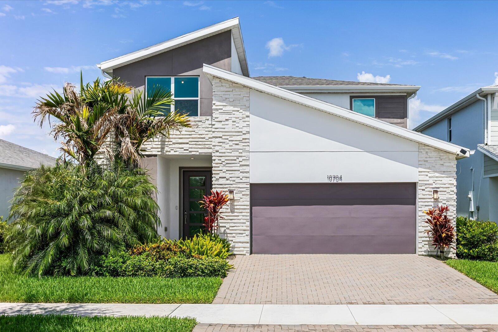 "Hey Siri... Search for gorgeous homes with lake views in Tradition!" Search no more! Built in 2022, this upgraded lakefront home in Emery at Tradition offers the perfect blend of modern style and comfort. The open concept layout features a spacious kitchen with a large center island, quartz countertops, stainless steel appliances, and a walk-in pantry, which is ideal for everyday living and entertaining. The chandeliers add an elegant touch to the dining area and primary suite, while upgraded Zebra shades, impact windows and doors, and hard flooring throughout complete the home's modern appeal. The primary suite features dual vanities and spacious his-and-hers closets.    The stairway leads you upstairs, where you can unwind in the spacious, comfortable flex room that opens into all 3 guest bedrooms and the guest bathroom. Additional highlights include a large laundry room, storage under the stairway, and a two-car garage for extra storage.  Whether you're hosting or unwinding with breathtaking lake views, this home offers the Florida lifestyle you've been searching for.  Residents of Emery enjoy 24/7 gated security, a community pool, and clubhouse. Best of all, you're just a short walk to Tradition Town Square, restaurants, Cleveland Clinic Tradition Hospital, and the exciting new park coming soon. Don't miss your opportunity to own this exceptional lakefront home in one of Tradition's most desirable communities. Schedule your private showing today!