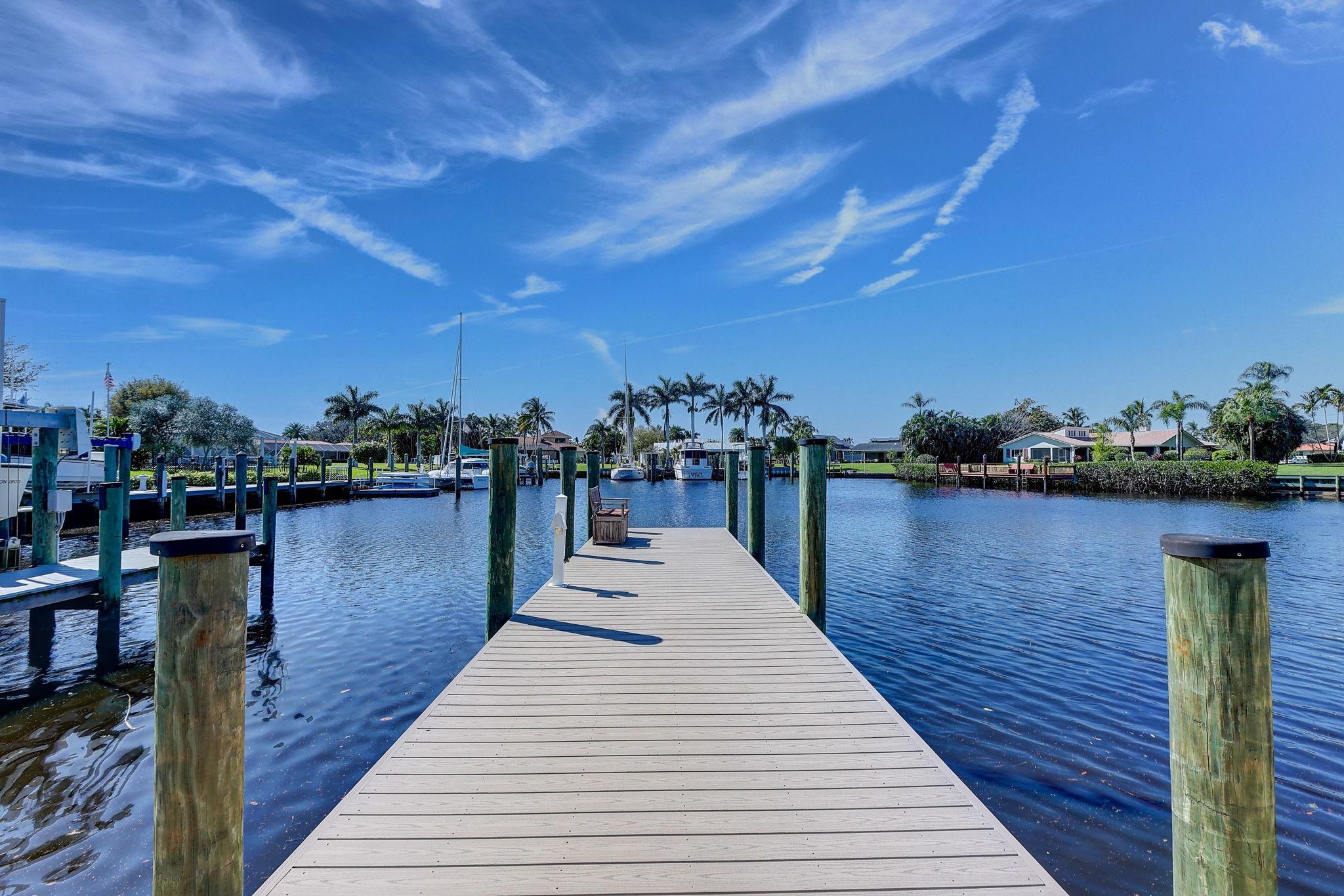 Spectacular Deep Water single story classic Florida home. This beautiful designer home sits on a large protected turning basin located off the North Fork of the St. Lucie River. It has been totally updated completed in 2023 and remodeled with complete sophistication. New gourmet kitchen, European wood cabinets, light Cambria quartz countertops, new appliances and updated bathrooms. Light travertine flooring in a French pattern and hardwood floors throughout.  All windows and doors are PGT impact glass. Excellent outdoor living space for Florida entertaining and a new private dock and seawall. Plenty of room for a 50-75 foot yacht and a 20,000 pound boat lift included. 2015 Metal roof, new A/C, new electrical wiring, Brick paver driveway. Privacy fenced lot. This is a must see!! One of the rare properties in Florida whereas the property line extends into 50 feet out into the canal basin.