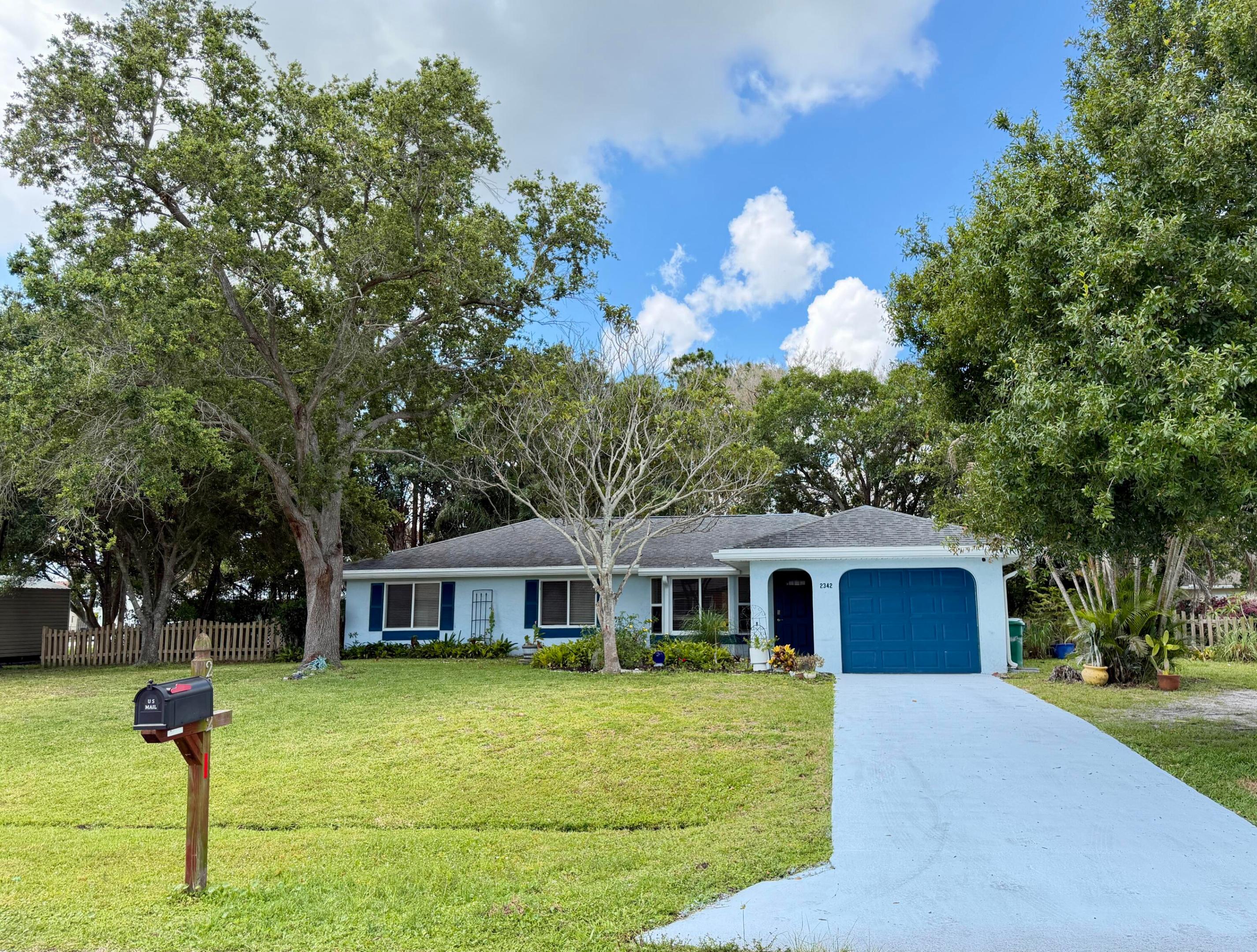 Great east location on .34 acre with mature trees in the spacious fenced yard. Foyer entry leads to open living area and beautiful backyard views. Three bedrooms with newer vinyl plank flooring. Updated baths. Primary has walk-in shower, double sinks & cabana door. Guest bath has a tub/shower combination & double sinks as well. Single car garage makes a great workshop with ample outside parking. Tons of room for a pool in the private yard. Newer AC and water heater. Close by shopping, parks, restaurants all along US1 and Port Saint Lucie Blvd. 1 block from Mariposa Elementary. Great opportunity to own the home on such a impressive lot east of US1!