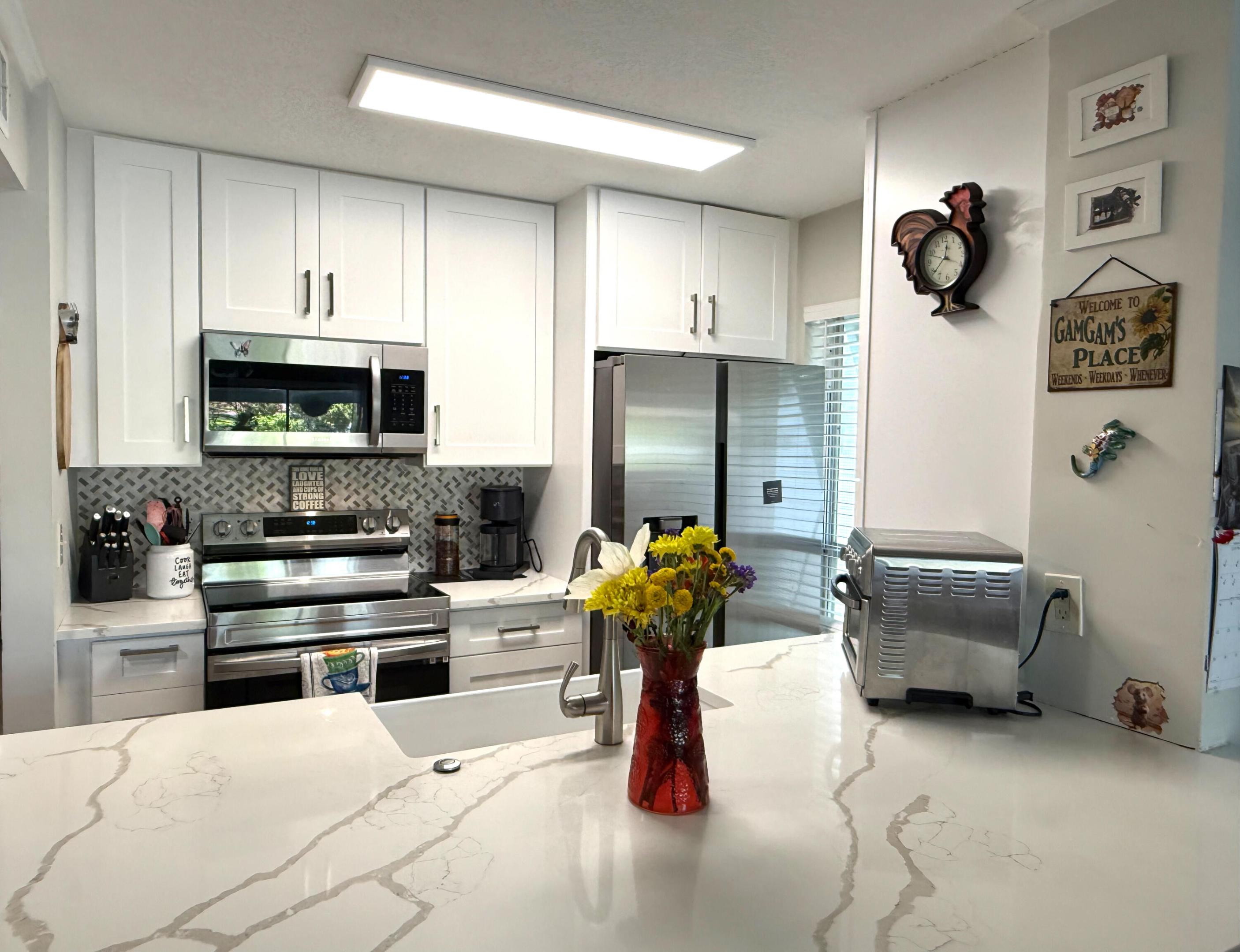 Motivated seller! Impeccably updated 1st floor condo in PGA National with an incredible lake view. Open kitchen with quartz counter, extra large pennisula for bar stool seating and has storage underneath, white shaker cabinets, large farmhouse sink, tile backsplash, pantry,  and all stainless steel appliances. New LED lighting throughout. Knockdown texture ceilings (no popcorn). All tile and luxury vinyl flooring (no carpet). Updated bathrooms with beautiful tile work, new vanities, and walk-in tub with jacuzzi features. New stackable GE washer and dryer in unit. Crown molding in the main living area. Screen enclosure on the screened patio was grandfathered in and one of few community with a screened patio. You get your money's worth with this condo! Can be rented out immediately as well.