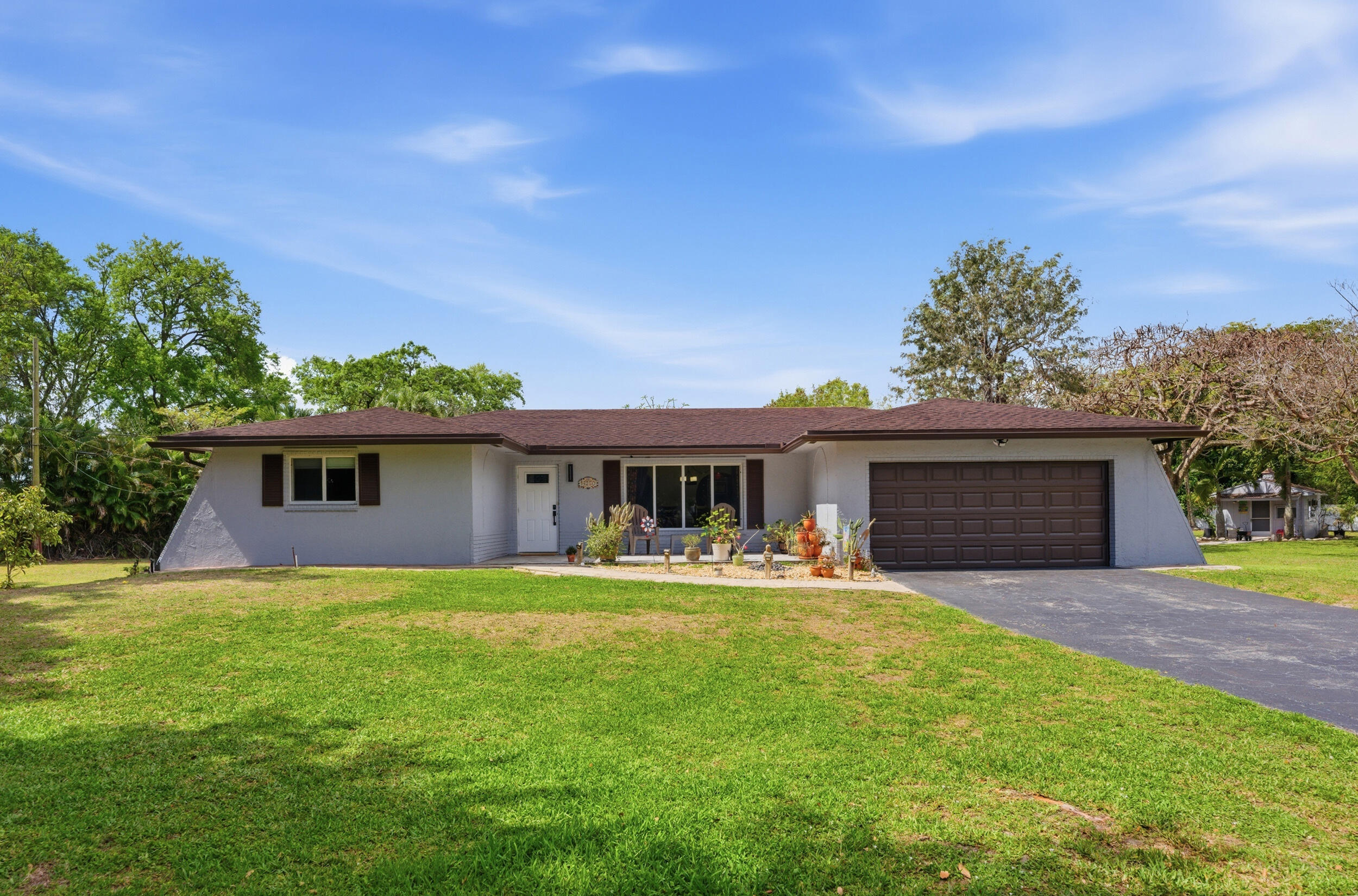 This rare 3 bed-2 bath gem sits on a full acre in a highly desirable area offering privacy and endless potential. Located on a private road and surrounded by lush greenery and fruit trees, this property creates a true private oasis. The light-filled interior features laminate flooring, an open layout, elegant archways, and multiple living areas including a spacious Florida room. The kitchen offers granite countertops, ample cabinetry, and custom backsplash. Upgrades include impact windows/doors, newer roof, newer AC unit, newer water heater, filtration system, and alarm. The oversized yard features a patio, shed, barn with plumbing, & room for pool, RV, or expansion. Conveniently located near major roads, shopping, & dining.  No HOA. Includes troy-bilt lawnmower and 6000-watt generator