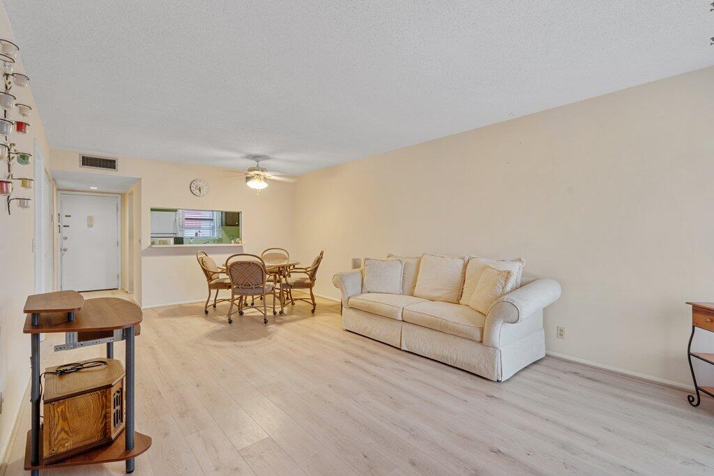 MOTIVATED SELLERS - Make an offer! Feel at home in this 1BR/1.5BA condo!  Open living space features newly redone flooring throughout, great natural light and a layout that offers space to relax along with easy maintenance.  This condo also features a private screened-in patio, perfect for that cup of morning coffee or relaxing in the evening.  This unit also has a personal storage space on the same floor.  The building roof was replaced in 2022.  Furniture is optional, making dining and bedroom move in ready.  This area features a well maintained 55+ community with multiple pools, clubhouse and shuffleboard area.  HOA covers cable, water, sewer, building insurance, exterior maintenance. Royal Palm Beach park, shopping, dining friendly with medical facilities nearby.
