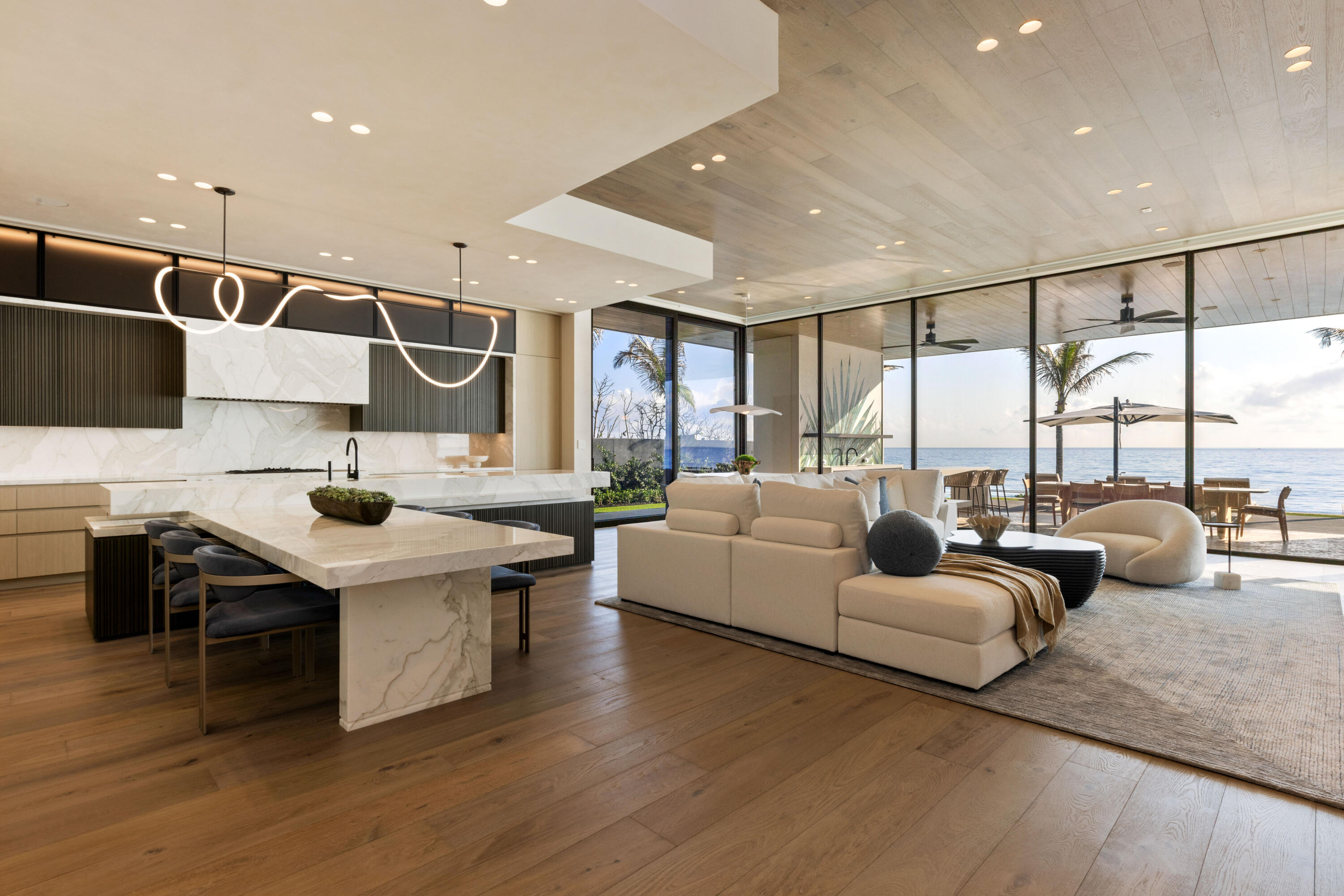 Set between the Atlantic Ocean and Intracoastal Waterway, 1160 S. Ocean Blvd is a rare retreat where architecture and nature exist in perfect harmony. Spanning 27,745± square feet under roof on nearly 2 acres, this newly completed estate offers 160 feet of direct ocean frontage and private Intracoastal access, creating an unrivaled connection to land and sea. Designed with balance and thoughtful craftsmanship, the 25,197± square-foot main house flows effortlessly from one space to the next. From the grand entry hall, the journey unfolds—a symphony of light and space, where the living room merges with the ocean beyond. The formal dining room, with its ocean-facing bar, sets the stage for elegant entertaining, while the open-concept kitchen and family area form the heart of the home. A private catering kitchen allows staff to work discreetly behind the scenes. The primary suite, occupying its own wing, features a private sitting room, ocean-view office, and dual dressing rooms. The spa-like primary bath, wrapped in Calacatta marble, offers a stone soaking tub and dual water closets. Three additional guest suites on the main level each provide private en-suite baths and walk-in closets. On the lower level, the home transforms into a haven of leisure and wellness, featuring a state-of-the-art gym, steam shower, wine room, game room, and immersive theater. Two additional bedrooms offer private accommodations for staff or extended family. From concept to completion, this home was orchestrated by female builder Siobhan Zerilla, principal of Bluedoor Building, bringing vision and artistry to every detail. For the automotive enthusiast, a climate-controlled 13-car garage provides the perfect space for a prized collection. A separate guest house offers two bedrooms, two full baths, a half bath, a full kitchen, dining area, and private laundry, while its own cabana and private pool create a secluded retreat. The outdoor spaces are equally intentional, with a covered courtyard and east-facing loggia, designed for meditation, relaxation, and celebration. A private dock, equipped with two boat lifts, allows effortless Intracoastal access for yacht owners and water enthusiasts. Every surface, every detail has been curated for those who expect the best. White oak wood floors add warmth, complemented by Santorini Shell Stone, which transitions from indoor elegance to outdoor serenity. The home's refined palette is completed with Calacatta Gold, Black Alexander Honed stone, bespoke plaster walls, mahogany, and white oak accents. This is more than a homeit is a journey, a sanctuary where every detail whispers serenity. 1160 S. Ocean Blvd, Manalapanwhere life finds its rhythm.