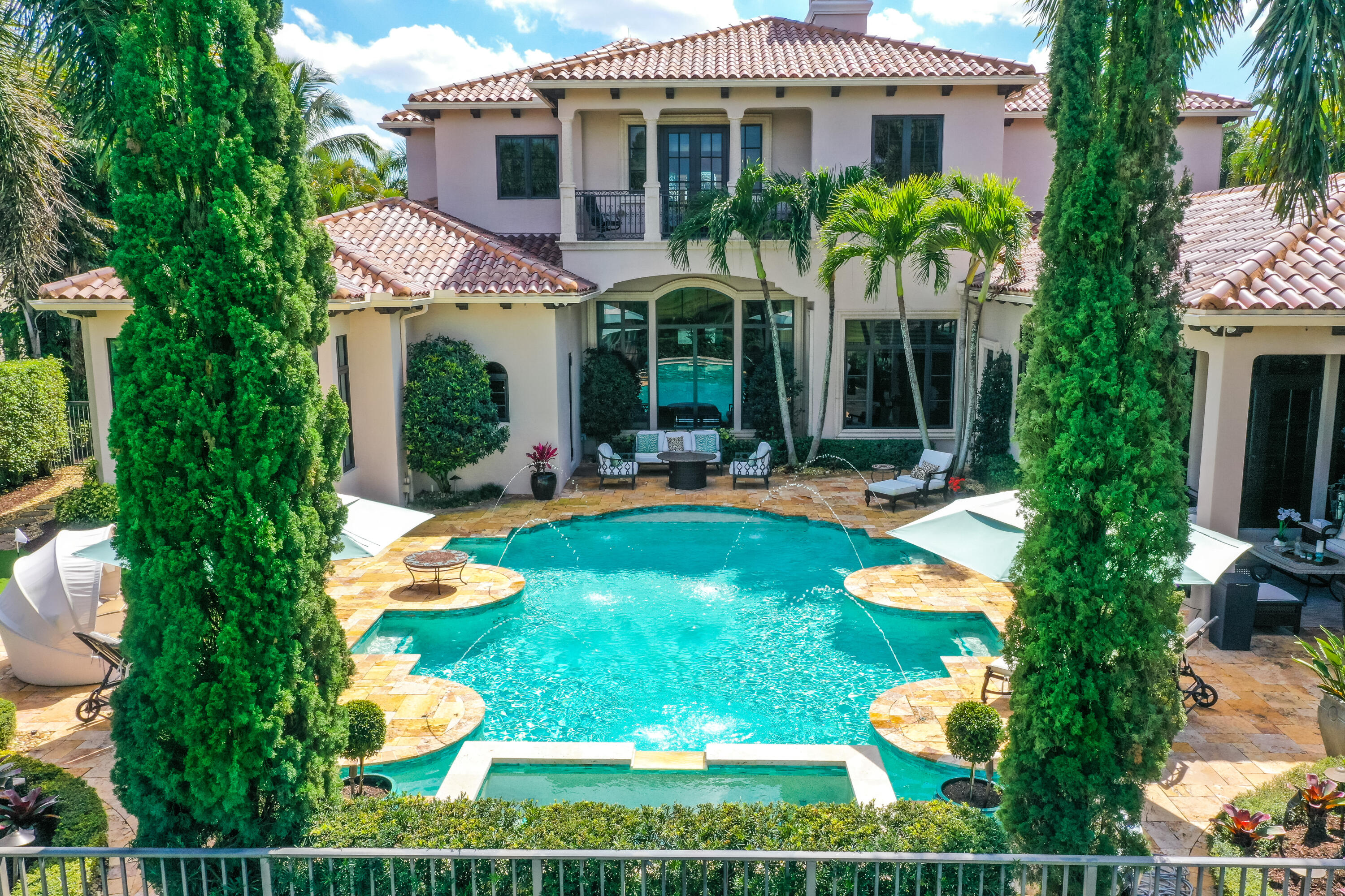 This expansive custom-designed estate offers exquisite finishes and craftsmanship that are a RARE find. Upon entering the voluminous foyer with a dramatic staircase you are greeted by the striking sun-filled living room with impressive vistas of the sparkling pool and lake. A culinary chef's dream, the kitchen offers gourmet appliances from Subzero, Wolf, Thermador, and Miele and a spacious walk-in pantry. With a seamless transition from the family room and quaint dining area to the club room, take note of the impressive finishes and custom woodwork throughout. A primary owner's wing on the main level of this nearly 7,000 SF home leads to a comfortable yet grand office/den. Approaching the owner's suite, the spectacular design and visual interest continues with dual luxurious bathrooms and walk-in closets that exceed expectations. The owner's suite has a private connection to the outdoor living space that reveals a resort-style saltwater pool and spa, putting green, luscious landscaping and long lake views. The loggia encompasses an outdoor living room with a bar and summer kitchen that takes entertaining to a whole new level. Up the grand staircase, you'll find a living room loft with gorgeous balcony views of the property and four spacious en-suite bedrooms, all unique in character. Located on a tree-lined estate section in The Oaks, this gated community offers resort lifestyle amenities including a private restaurant, gym, spa, and award-winning tennis facility that encompasses a 25,000 SF renovated clubhouse.