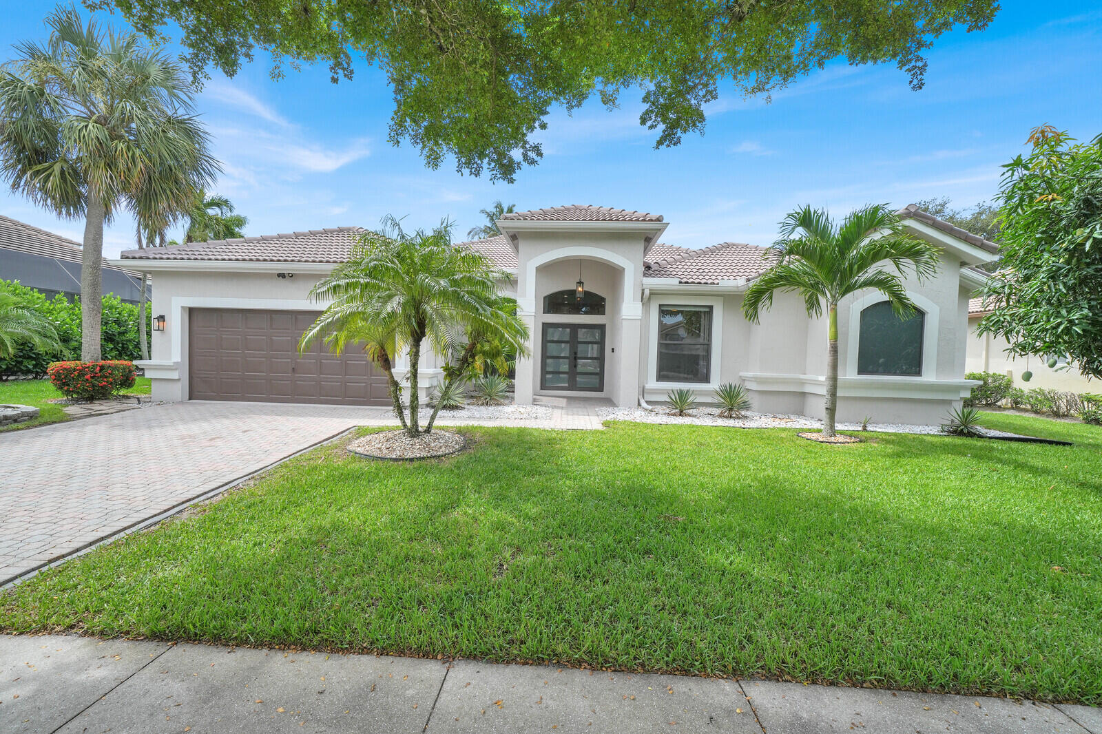 Luxury, privacy, and breathtaking lake views come together in this meticulously upgraded 5-bedroom, 4-bathroom residence offering 2,800 square feet of thoughtfully designed living space in the highly sought-after Lexington Estates of Boca Raton.  Inside, the home showcases a beautifully designed open layout with large modern tile flooring throughout the main living areas and engineered hardwood flooring in the bedrooms. The stunning kitchen features a center island, soft-close illuminated cabinetry with pull-out shelving, and a pantry.  Its functional design is perfect for both everyday living and entertaining.  The luxurious primary suite offers a private retreat with a spacious layout and a beautifully appointed en-suite bathroom featuring dual vanities, a separate   glass-enclosed shower, soaking tub, dedicated vanity seating area, and a large walk-in closet with custom built-ins for exceptional organization. The home also offers a large second bedroom with an en-suite bathroom, an additional playroom, and a dedicated home office, providing exceptional flexibility. Thoughtful upgrades throughout include impact windows and doors, a SpringWell whole-house water filtration system, garage with epoxy floors and custom storage, security cameras surrounding the property with a video doorbell, and all-electric utilities.   Step outside to the resort-style backyard designed for entertaining - with a heated saltwater pool, cabana bath, outdoor shower, and a built-in entertainment area complete with a TV and speakers. A mature mango tree and panoramic lake view add the perfect tropical finishing touches. The south-facing backyard is bathed in sunshine throughout the day, creating the ideal setting for year-round outdoor living.   Residents of Lexington Estates enjoy a beautifully maintained gated community featuring a heated resort-style pool, tennis and  pickleball courts, basketball courts, a playground, and a private gated entrance to the neighborhood elementary school with dedicated security guard.   This exceptional home - nestled lakeside in the back of the community  -  offers a rare combination of utmost privacy, thoughtful upgrades, and resort-style amenities in one of Boca Raton's most desirable communities.