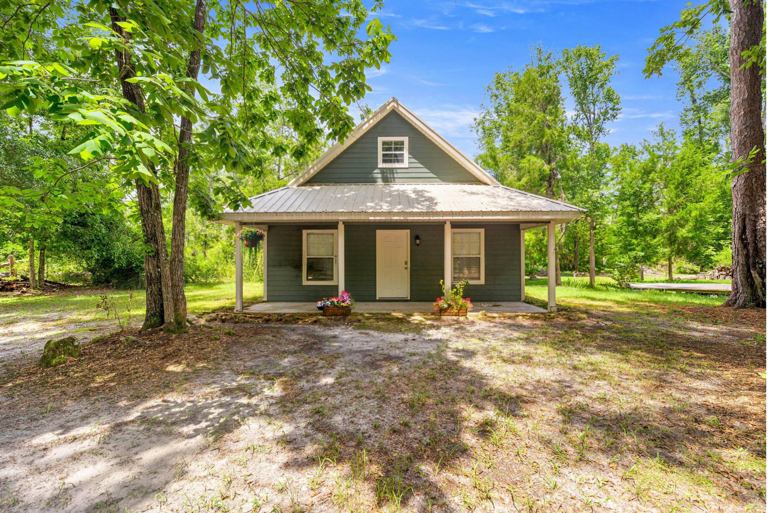 Experience the ultimate nature retreat in this immaculate 2009-built A-frame, secluded on 5 gated acres at the edge of the Ichetucknee Wilderness. Located at the very end of a private road, this modern 3-bedroom, 2-bathroom cabin features soaring vaulted ceilings and a sun-drenched, airy layout perfect for a full-time residence or a lucrative short-term rental.  The outdoor living spaces feature a stargazing deck with a gas fire pit, a traditional fire pit, and a custom wooden deck currently outfitted for a large glamping yurt. A standout feature is the pure, spring-fed water system sourced directly from an underground head spring, delivering crystal-clear Florida water to every tap. Additional highlights include a charming "mini-replica" shed with tiny-house potential and a high-and-dry elevation. Offered fully furnished (with an unfurnished option), this turnkey-sanctuary is just minutes from the Ichetucknee Springs North entrance, offering unparalleled access to forest trails, local wildlife, and serene natural beauty.