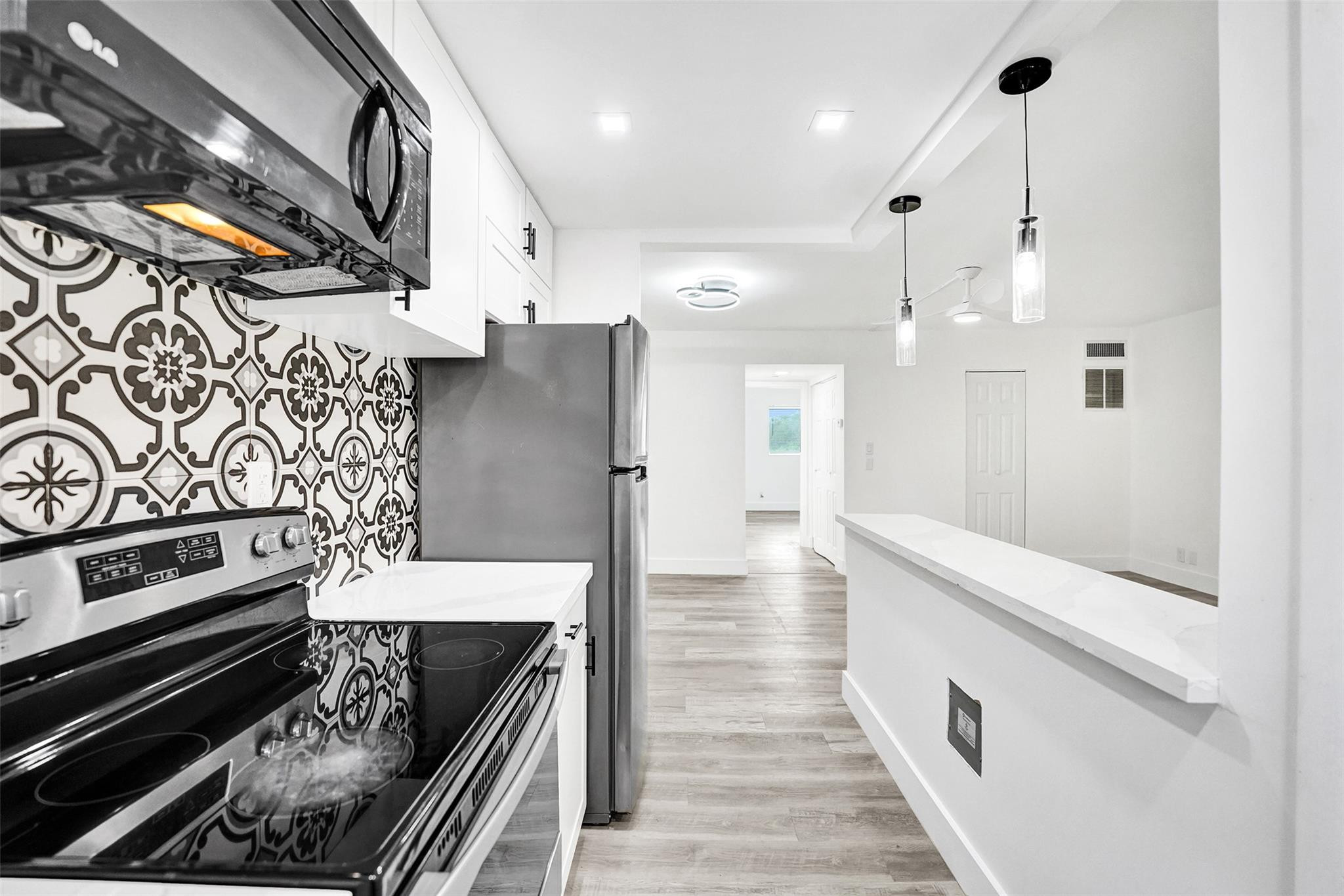 Modern coastal living East of US-1! This beautifully refreshed 1BR/1.5BA residence at Santa Monica Condo features sleek vinyl flooring, clean lines, and soft neutral tones. The designer kitchen boasts stone countertops, stainless steel appliances, white cabinetry, a custom tile backsplash, and a breakfast bar. The spacious primary bedroom offers generous closet space, while both bathrooms feature contemporary finishes and modern vanities. Enjoy a screened patio perfect for sunset views. This pet-friendly building offers a community pool, sauna, assigned parking, and storage. Ideally located minutes from Hollywood Beach, the Broadwalk, nature preserves, dining, and FLL Airport. Hurricane impact windows and doors provide peace of mind. Ideal as a primary residence or a coastal retreat.