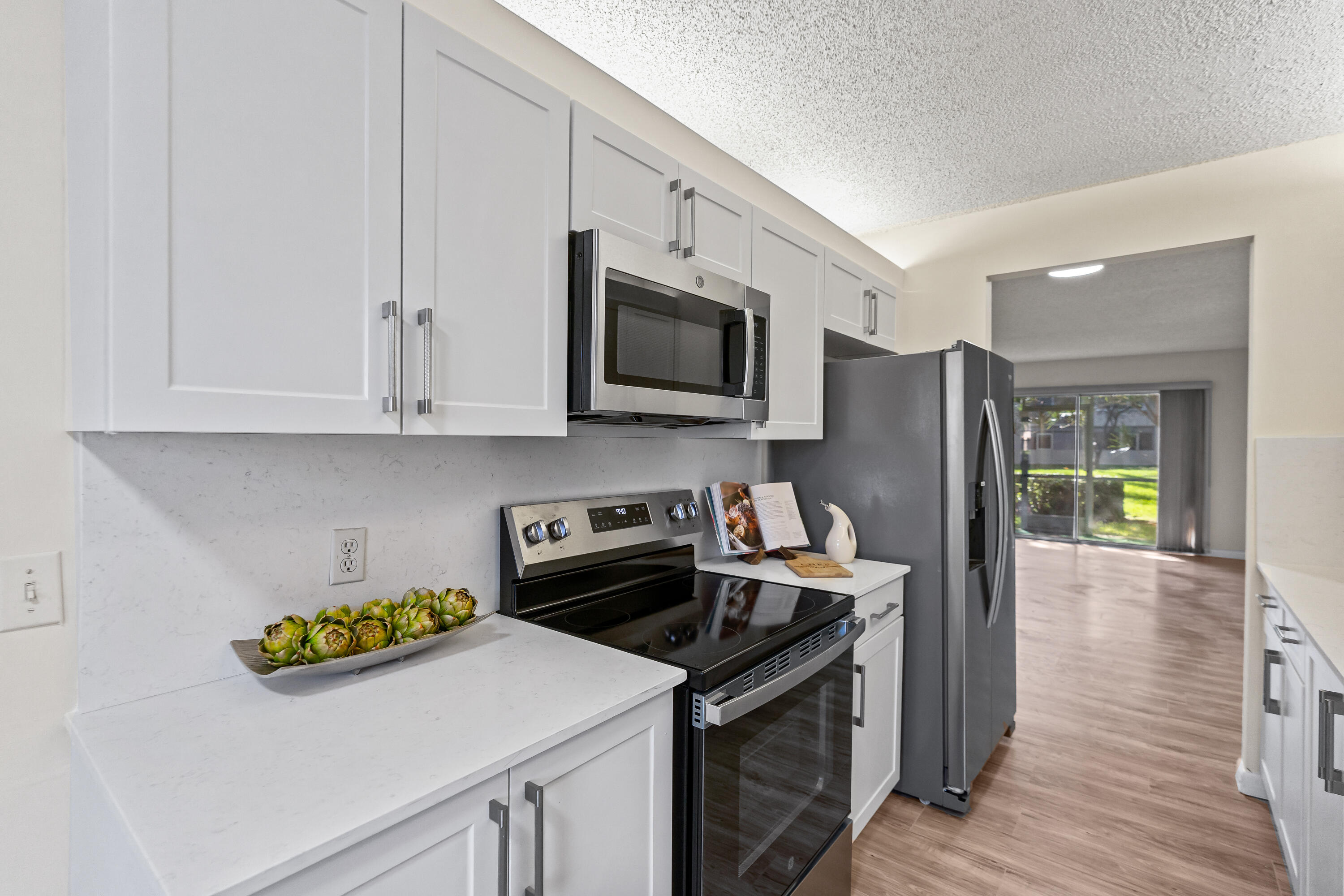 Beautifully renovated 2 BD, 2 BA first-floor condo in Century Village! Recent improvements include new laminate flooring throughout, fresh interior paint, a completely renovated kitchen with new shaker-style cabinets, quartz countertops & backsplash, sink, faucet, and new stainless steel stove & microwave. Both bathrooms feature new vanities with under-mount sinks and modern fixtures. Enjoy the convenience of an in-unit stackable washer and dryer. Includes a newer refrigerator, dishwasher, A/C and 2017 water heater. Spacious split-bedroom floor plan with abundant storage and a screened patio. Conveniently located near Pembroke Gardens, and the Pembroke Lakes Mall for shopping & dining, medical facilities, and major roadways. Enjoy access to Century Villages' 135,000 sq ft clubhouse featuring a fitness center, indoor and outdoor heated pools, spa, sauna, tennis courts, pickleball courts, golf course, billiards room, library, and a grand ballroom with live entertainment and social events. The community also offers clubs, classes, and activities for an active lifestyle. Additional conveniences include 24-hour security and a courtesy shuttle providing transportation throughout the community and to nearby shopping, restaurants, and medical facilities. Monthly HOA includes water, cable, internet, exterior maintenance, and full access to all amenities. This first-floor condo offers added convenience and accessibility with easy entry and no stairs, making it an ideal choice for comfortable, low-maintenance living in Pembroke Pines. Convenient parking spot T-34 just right outside the unit near the mailboxes.
