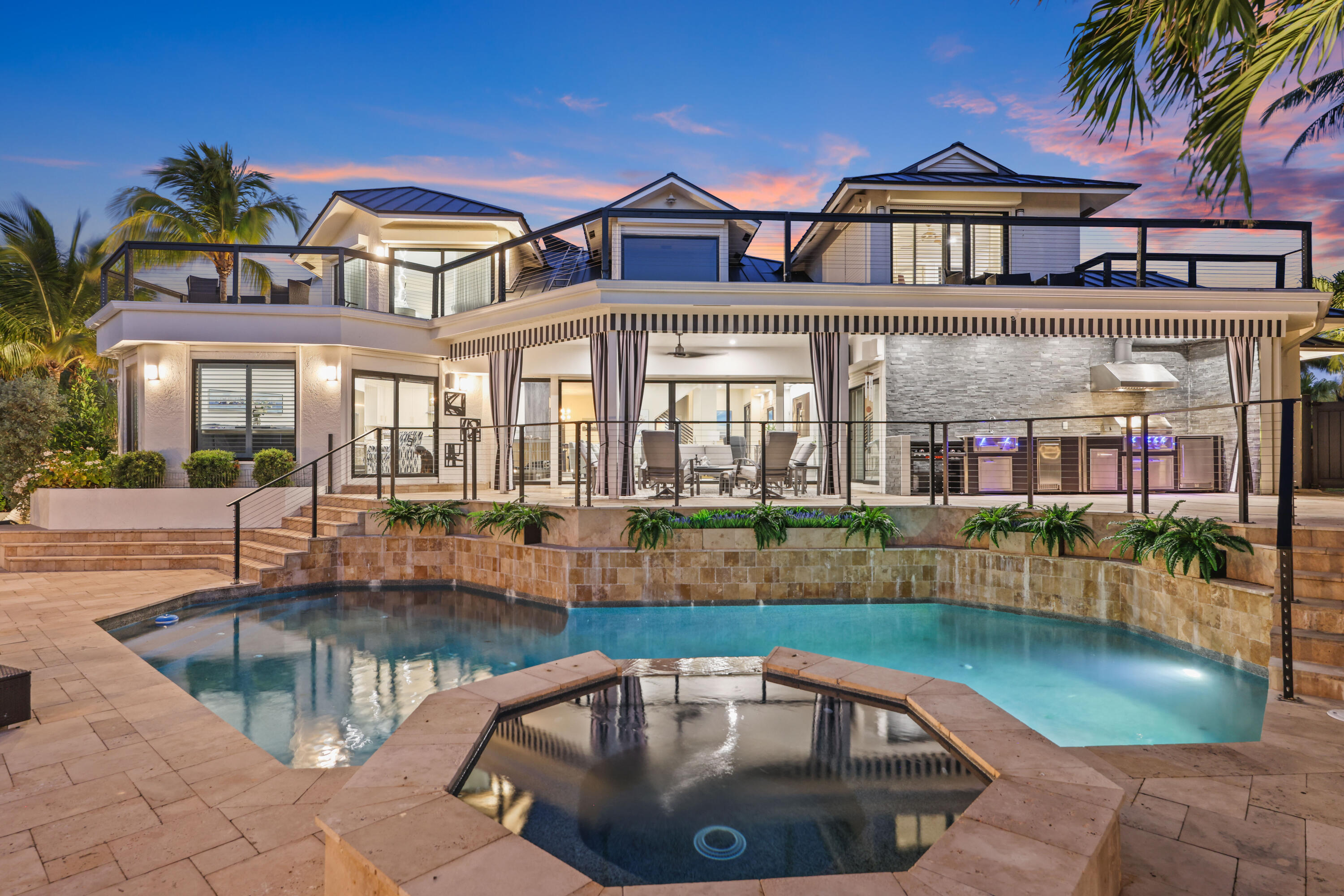 Welcome to the epitome of waterfront living in Ocean Ridge, just minutes south of iconic Palm Beach Island. This stunning two-story contemporary home offers the ultimate blend of design, comfort, and lifestyle. Ideally positioned on a deep-water canal with a 92-foot dock and just five minutes from the ocean, it's a dream setting for boating enthusiasts. Designed by acclaimed New York interior designer Joseph Stabile of JR Cattington Design, every detail of this five-bedroom, five-and-a-half-bath residence exudes elegance and sophistication. Each bedroom features its own en-suite bath, providing privacy and luxury for residents and guests alike. The expansive open floor plan flows seamlessly from the warm and inviting media room to the large, eat-in kitchen outfitted with a premium Thermador appliance package. The home's heart extends outdoors to a grand pergola, ideal for al fresco dining, complete with a full outdoor kitchen including a gas grill, large griddle, ice maker, refrigerator, and sink.  Retreat to the serene primary suite, where your spa-like bathroom awaits featuring a steam shower, a soaking tub, and direct access to a private terrace overlooking the tranquil water. Impressive large walk-in closet, bathed in natural light and framed by water views, add to the suite's allure.  Step outside to your lushly landscaped oasis, surrounded by verdant greenery and swaying palm trees. The heated pool and spa anchor a spacious patio built for entertaining under the Florida sun. The dock is complete with custom-built cleats, piles, whips and fenders that will accommodate a vessel up to 60 ft. This Ocean Ridge estate offers not just a home but a refined, relaxed lifestyle by the sea.   Key Features:  As a Harbor Island resident you will have access to the private McCormick Mile Beach Club which sits just moments away. Spend the day with your family enjoying the sand and surf, then return home to your gorgeous estate on the water.  State of the art best in class full house water purification system  Hurricane glass throughout the entire home along with steel roll -down shutters for added security and protection.
