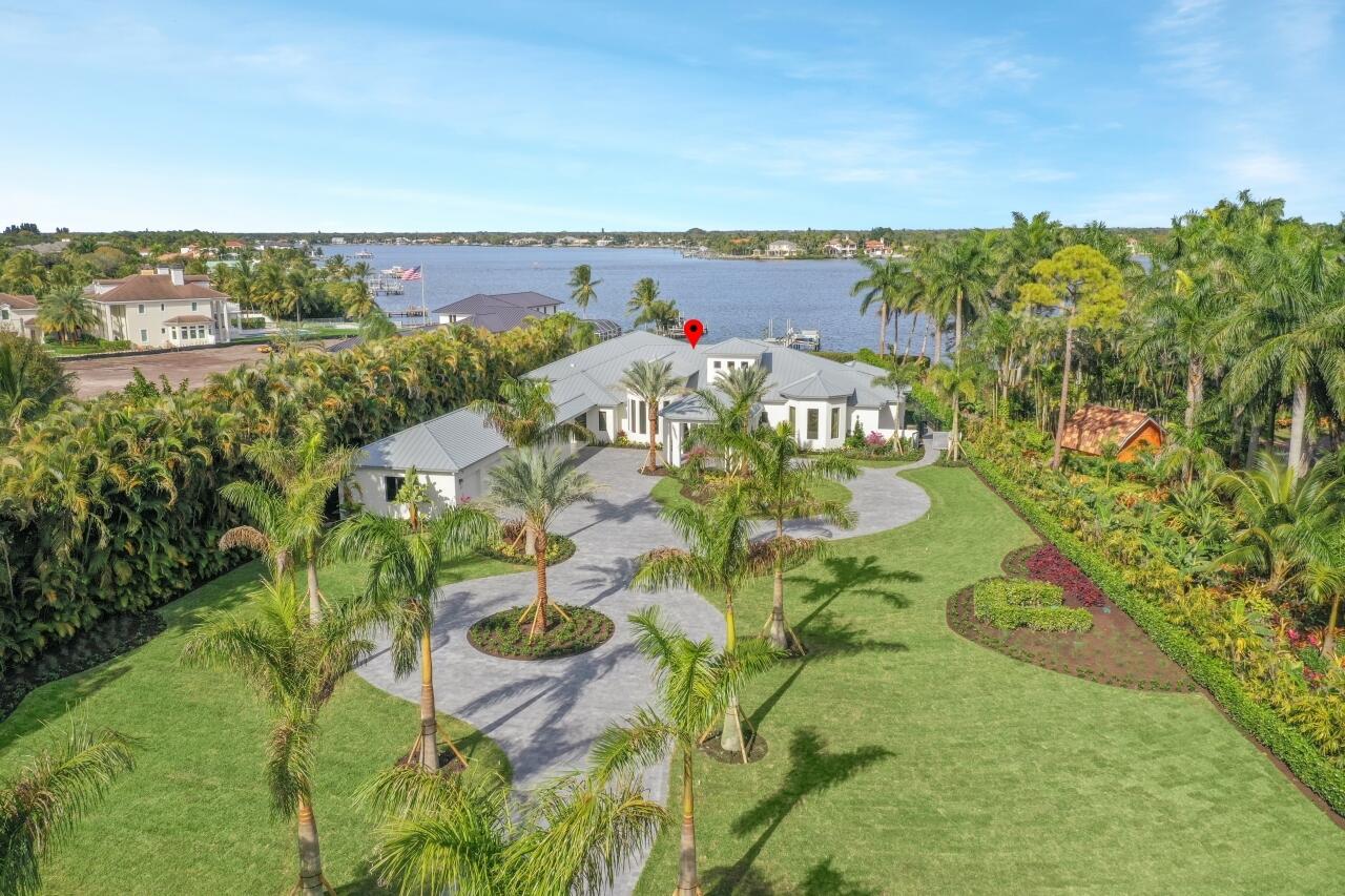 Click the link under the main photo for video and 3D tour of this amazing home as well as a video tour of Jupiter. As you pull into the private gates, you are immediately welcomed  to your expansive riverfront estate by the palm tree lined double circular driveway.  This modern marvel sits on just under 1.7 acres. The home, which was originally built by Neandross Builders, has been completely reimagined, redesigned and totally reconstructed down to the studs by the highest quality builder, Onshore Construction. Some of the many features include volume ceilings, new grande pivot front door, impact windows & sliding doors providing sweeping wide river views, extensive custom cabinetry, built-ins, and highest quality appliances throughout. The spacious formal living and dining rooms flow gracefully into the stunning chef's kitchen, family room, bar/club rooms and out to the spacious lanai, outdoor kitchen, pool and spa making this home an entertainers dream. The luxurious owner's suite includes an elegant custom dressing area, walk-in shower, freestanding soaking tub, morning bar and spacious bedroom with views most only dream of waking up to. With lush landscaping, a custom redesigned infinity edge salt-water pool and spa, spacious lanai with custom outdoor kitchen, private dock with 12,000 lb lift and a lift for 2 jet ski's completes this dream home. Love where you live. Come home to 5695 Pennock Point Road!