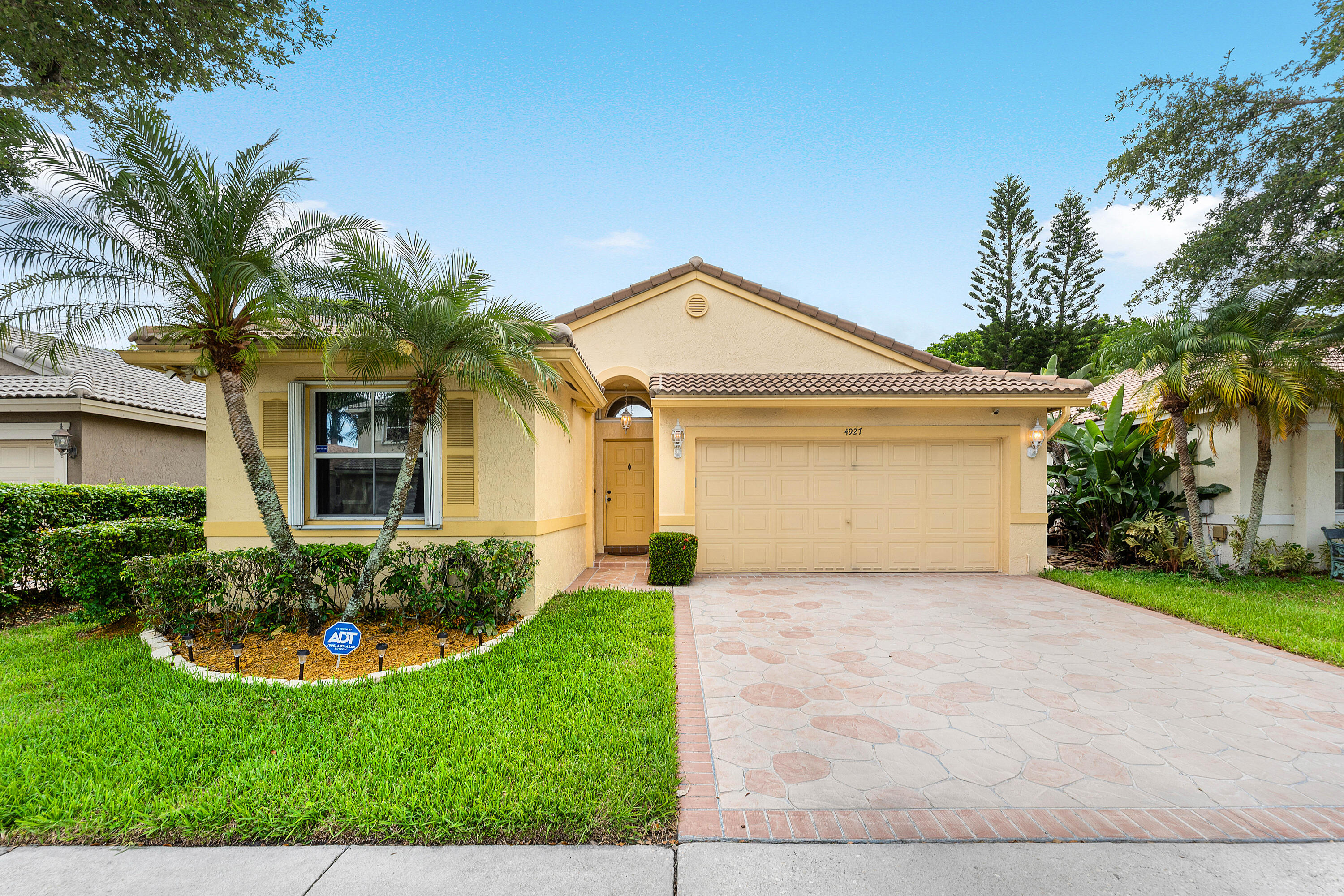 Welcome to this impeccably maintained residence where comfort, elegance, and peace of mind come together effortlessly. Surrounded by lush tropical landscaping and enhanced by beautiful curb appeal, this light filled home offers soaring ceilings, spacious living areas, and an inviting open layout designed for both everyday comfort and entertaining. The interior showcases tile flooring, generous natural light, and seamless flow throughout the living, dining, and kitchen spaces. Thoughtful details and meticulous upkeep create a warm yet refined atmosphere from the moment you enter.  Step outside to a spacious 300 sq. ft. screened and covered patio overlooking a private backyard retreat with mature greenery and tranquil surroundings. Complete with a brand new fan and lighting, this outdoor space is perfect for relaxing mornings, evening gatherings, or year round South Florida living.  Recent upgrades add exceptional value and convenience, including a 3 year old roof, hurricane shutters, generator hookup, new hot water heater, washer, dryer, sprinkler controller box, and brand new dishwasher. The included Bose Lifestyle Home Entertainment System elevates the living experience and a transferable roof warranty provide added confidence for the next owner. Beautifully cared for and truly move in ready, this residence offers the perfect blend of comfort, style, and long term peace of mind.