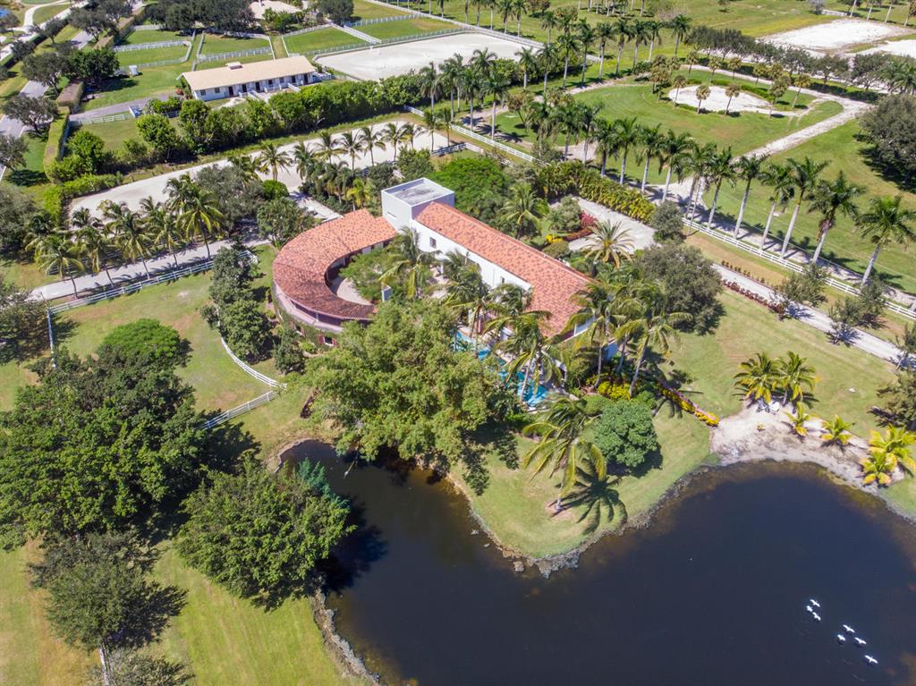 Located in the exclusive enclave of Palm Beach Point this property has it all. From the contemporary design to the round barn  The 4 bedroom 4.5 bath no detail missed. This home promotes the open concept, an abundance of natural light and privacy. There is a large flex space suite with  loft that is attached to the main residence. Perfect for an in-law residence. The 7 stall open round barn is centered on the circular courtyard with mature landscaping. This design concept promotes a healthy environment for the horses with constant air circulation. The barn can be expanded to 12 stalls with the design plans complete. There is a large riding arena and ample paddocks. There are 2 entrances,  one for the residence and the other for the barn with ample parking for cars & trailers.