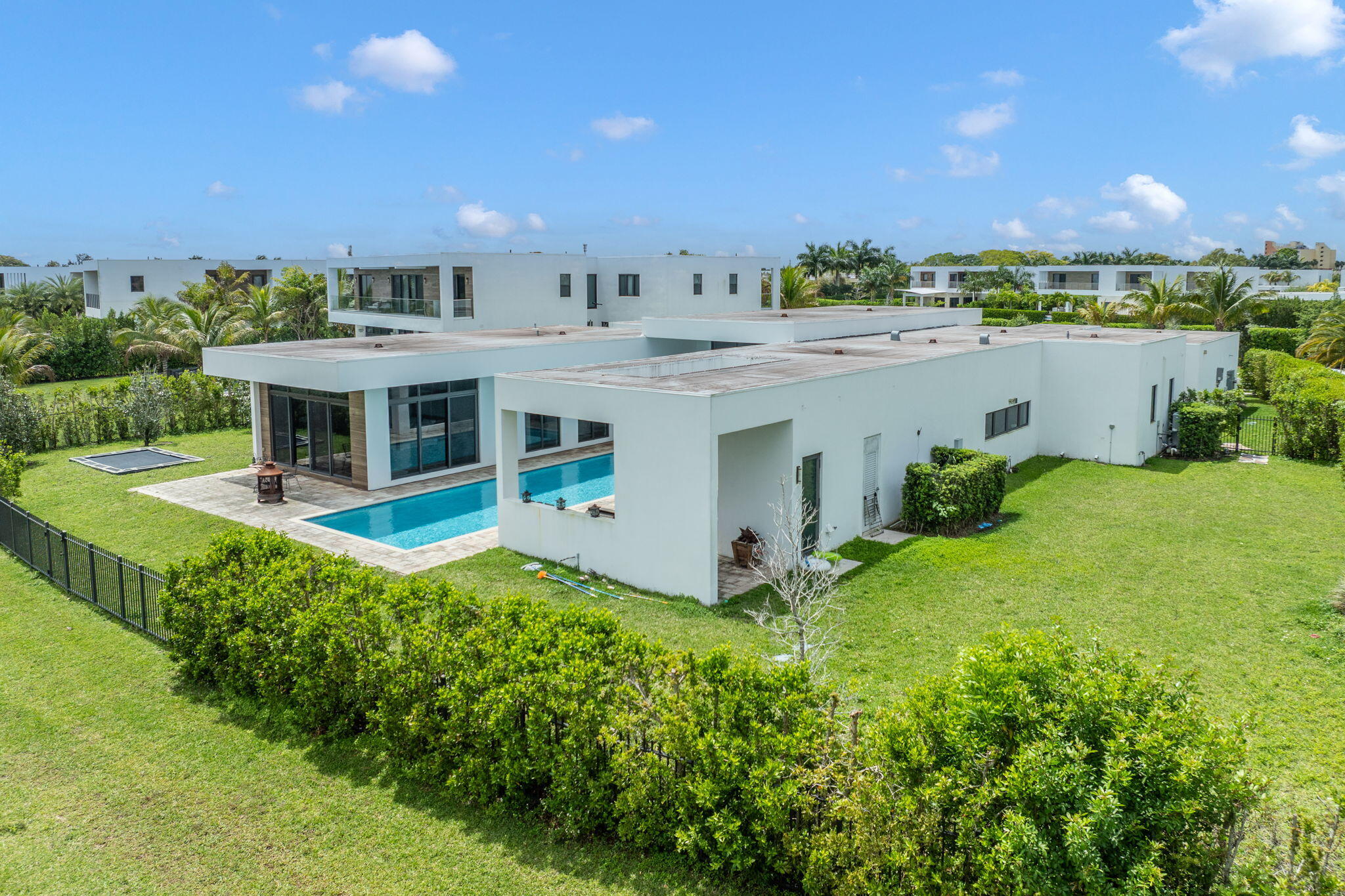 Tucked within the exclusive gates of Botaniko Weston, where modern architecture meets the serenity of nature, there is a home that doesn't simply exist, it unfolds like a quiet masterpiece. Set on one of the most coveted, and largest, lots in the community, spanning an impressive 27,362 square feet, this one-story residence stretches gracefully across 7,293 square feet of refined living. From the moment you arrive, the clean lines and bold architectural presence hint at what lies within: a home designed not just to impress, but to elevate everyday living.  Step inside, and space reveals itself in breathtaking fashion. Soaring 20-foot ceilings draw your eyes upward, while natural light pours in, reflecting off sleek finishes and framing tranquil lake views that follow you from room to room. The layout flows effortlessly, open, expansive, and intentional, creating a seamless connection between living, dining, and gathering spaces. At the heart of the home, the kitchen becomes a statement of both design and function. Outfitted with world-renowned appliances, Wolf, Sub-Zero, and a built-in Bosch coffee system, it invites everything from quiet morning rituals to vibrant evenings filled with conversation. Every detail has been curated for those who appreciate precision, beauty, and ease. Six beautifully appointed bedrooms, along with a private staff suite, offer comfort and privacy for both family and guests. Each of the 7.5 bathrooms feels like a personal retreat, echoing the home's modern elegance with clean lines and luxurious finishes. And then... the outdoors becomes an extension of the experience. The oversized pool stretches across the backyard like a private resort, reflecting the sky and the water beyond. An expansive outdoor kitchen sets the stage for unforgettable gatherings, weekend celebrations, sunset dinners, or simply the quiet luxury of living well. Thoughtful additions, like electronic window screens and even an in-ground trampoline, bring together sophistication and play in a way that feels effortless. But what truly defines this home is its setting. Living in Weston is about more than just a beautiful address, it's a lifestyle. Known for its tree-lined streets, top-rated schools, and a sense of calm rarely found in South Florida, Weston offers a balance between elegance and ease. From morning walks through peaceful neighborhoods to evenings at nearby parks, golf courses, and the vibrant Weston Town Center, with its dining, boutique shopping, and community events, life here feels curated, intentional, and connected. And within Weston, Botaniko stands apart. A newer, architecturally distinct enclave inspired by modern design, it attracts those who seek privacy, innovation, and a home that reflects a global sense of style. This is more than a property. It's a place where design meets lifestyle... Where every space invites connection... And where arriving home feels like stepping into something truly extraordinary.