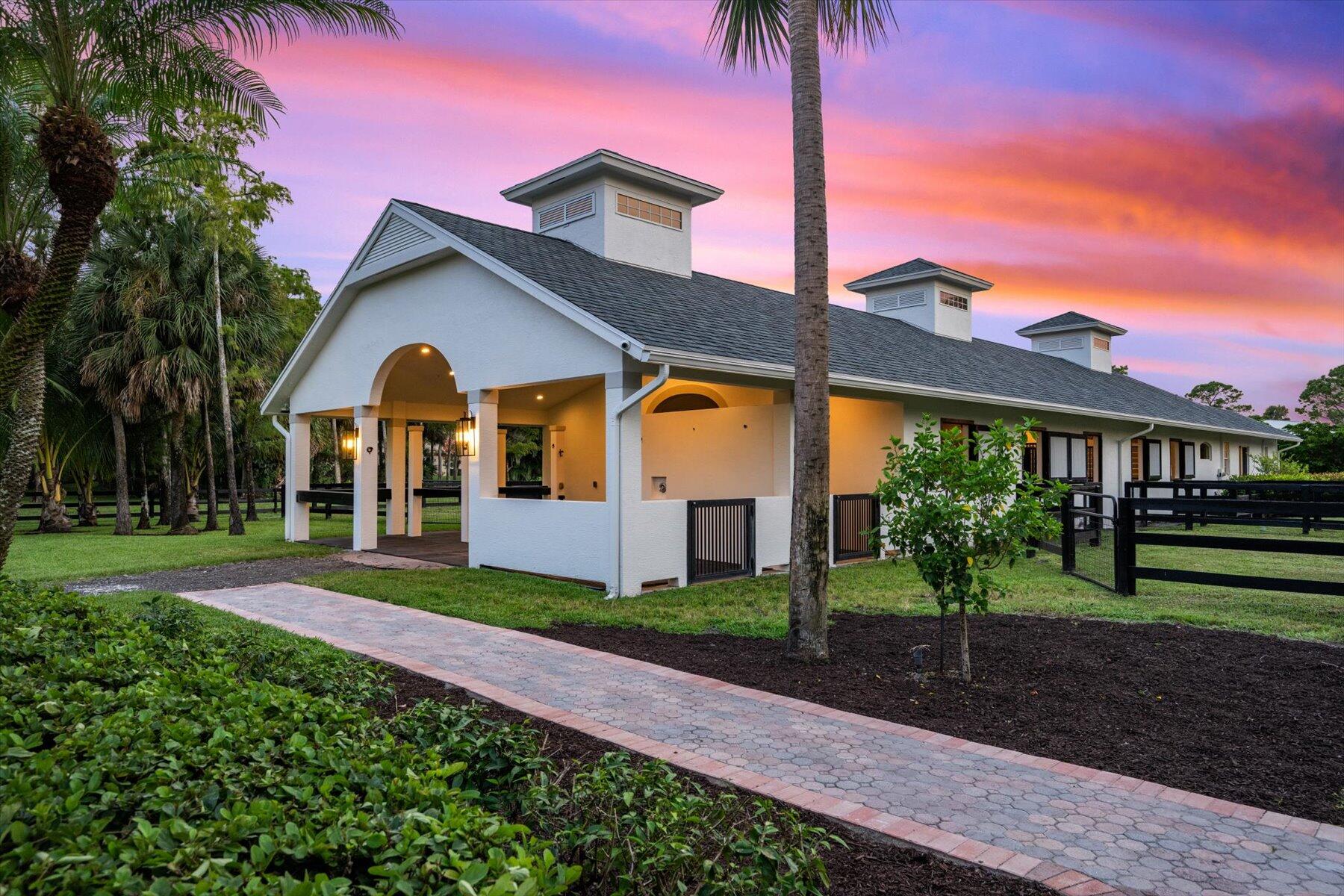 Set on just under 2.4 acres in the highly sought-after Paddock Park 2 community, this extraordinary property combines refined living with world-class equestrian amenities—all just minutes from Wellington's premier showgrounds.
The spacious 5-bed, 3.5-bath residence has been beautifully refreshed with newly refinished cabinetry, new flooring, and fresh paint inside and out. A brand-new pool deck, resurfaced pool, updated fencing, lush landscaping, and a modernized exterior create a true turnkey home designed for both comfort and style.
For the equestrian, the property delivers exceptional facilities: a 10-stall center-aisle CBS barn complete with a staff apartment, rider's lounge, covered wash and grooming stalls, plus dedicated tack, feed, and laundry rooms.  An expansive 210' x 100' arena with a GGT fiber footing mix provides the perfect environment for training and competition, while six paddocks (with room to add more) ensure ample turnout space.
Offering the rare balance of luxury living and professional-grade equestrian infrastructure, this property is more than a home it's a private retreat designed for the dedicated rider.