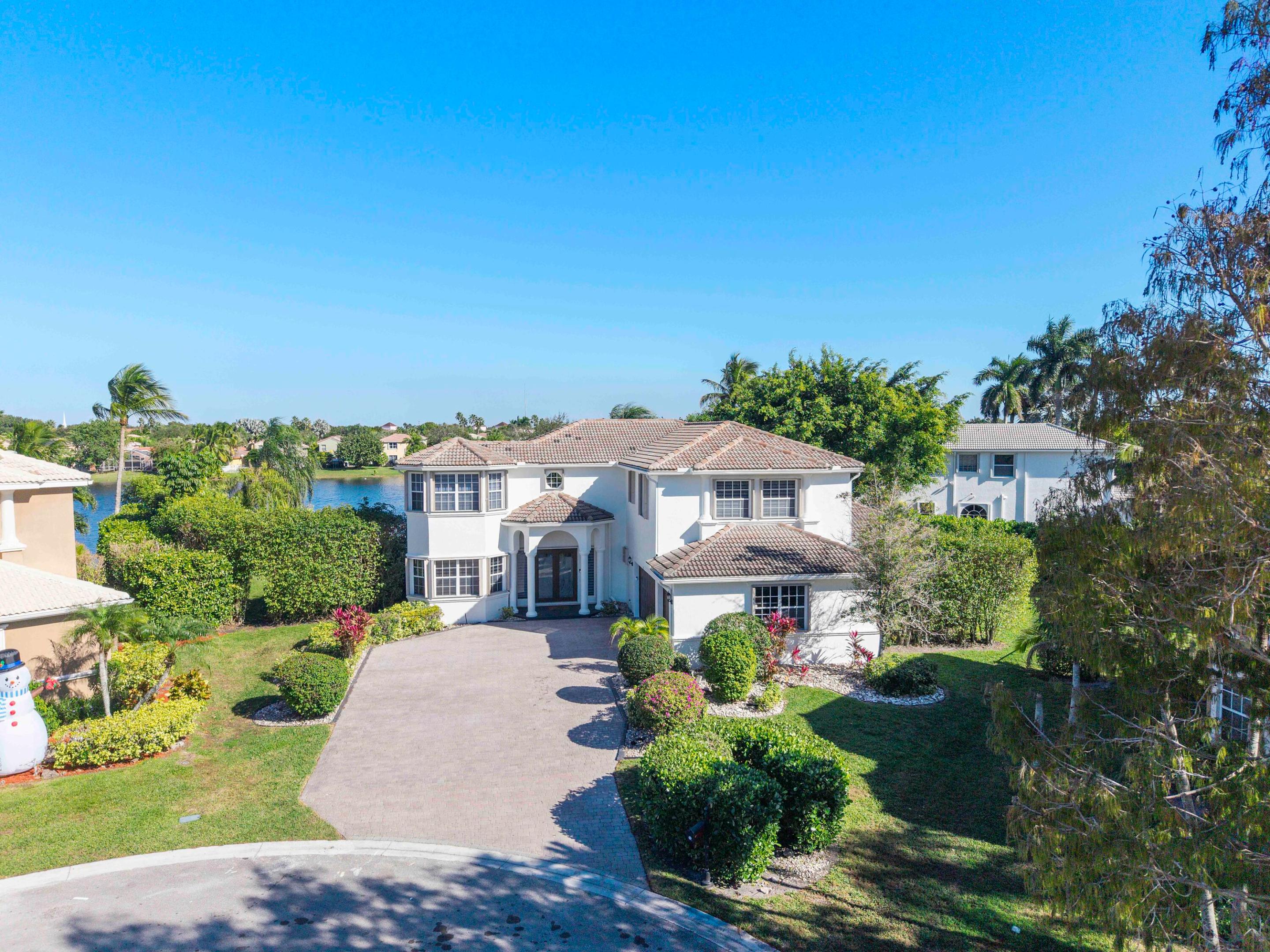 Newly updated Modern Kitchen, Primary & Guest Bathrooms,  AND 1st floor 24x48 Luxury Tile Flooring! Move-in ready! Resort lifestyle! This colossal 7-BR waterfront estate is the largest in the community, set on a rare .38-acre cul-de-sac lot. Enjoy total privacy with panoramic lake views. Soaring 20' ceilings. The massive primary suite offers a private sitting area and spa-like bath. Outside, an entertainer's paradise features a 27' covered lanai, outdoor kitchen, and heated pool, surrounded by lush tropical landscaping. Side-entry 3-car garage with parking for 8. First floor 20x20 wing functions as an office / 7th bedroom or rec room. Premier guard-gated community. HOA includes 24/7 monitored life-safety/intrusion security. Accordion Shutters throughout!