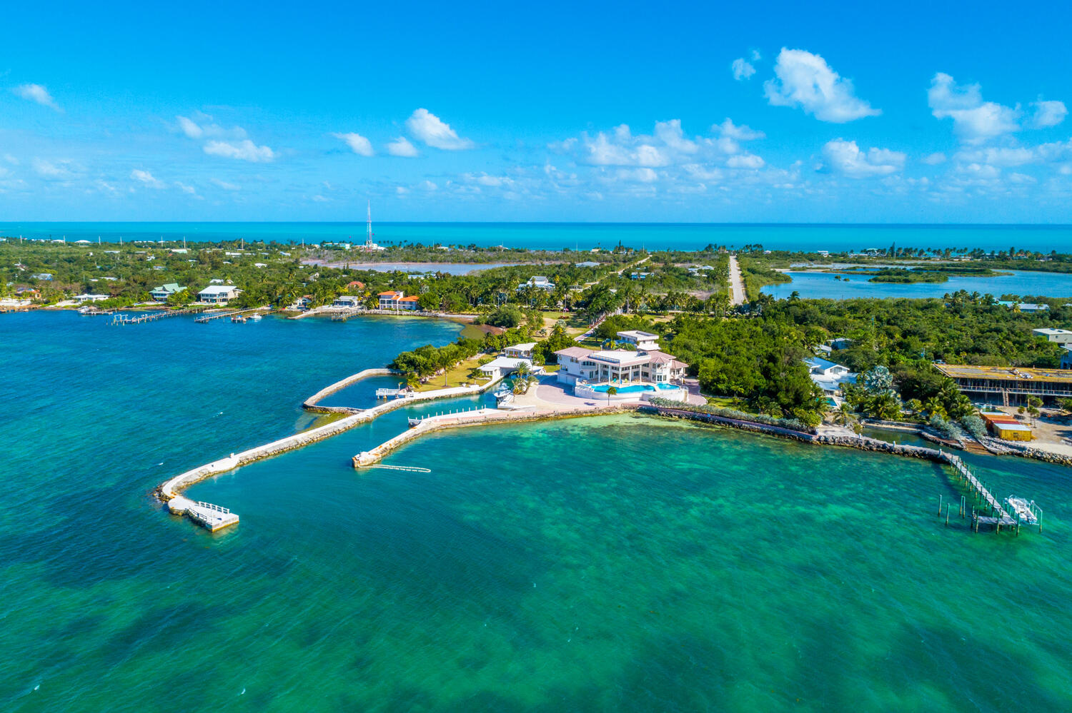 Paradise Found in The Florida Keys! Rare opportunity in Marathon, Grassy Key to own your own private compound perched on 5.5 blue waterfront acres as well as owning 5.25 Acres of Bay Bottom. This is truly a boater's dream. The private gates open and 100 Ft. Royal Palms line the driveway to welcome you and your family. Tropical breezes blow through the over 200 Palm Trees. Just off the Main House with its incredible infinity edge pool is the 2 garage boat house with private captains quarters. This property has its own private boat basin with 500 Ft private pier. A Salt water Coral Grotto with Lobster Farm. Bring your Sport Fisher, Flats Boats and Jets Skis to fish and explore all the Florida Keys has to offer from your backyard. Sip cocktails and enjoy the incredible sunsets over the bay. Just a few minute boat ride to the best fishing and scuba diving in all of the Florida Keys. Separate 2 bedroom guest house and workshop with 1 bedroom apt for grounds keeper. Private Jet access only 10 minutes from property.Truly a WOW!