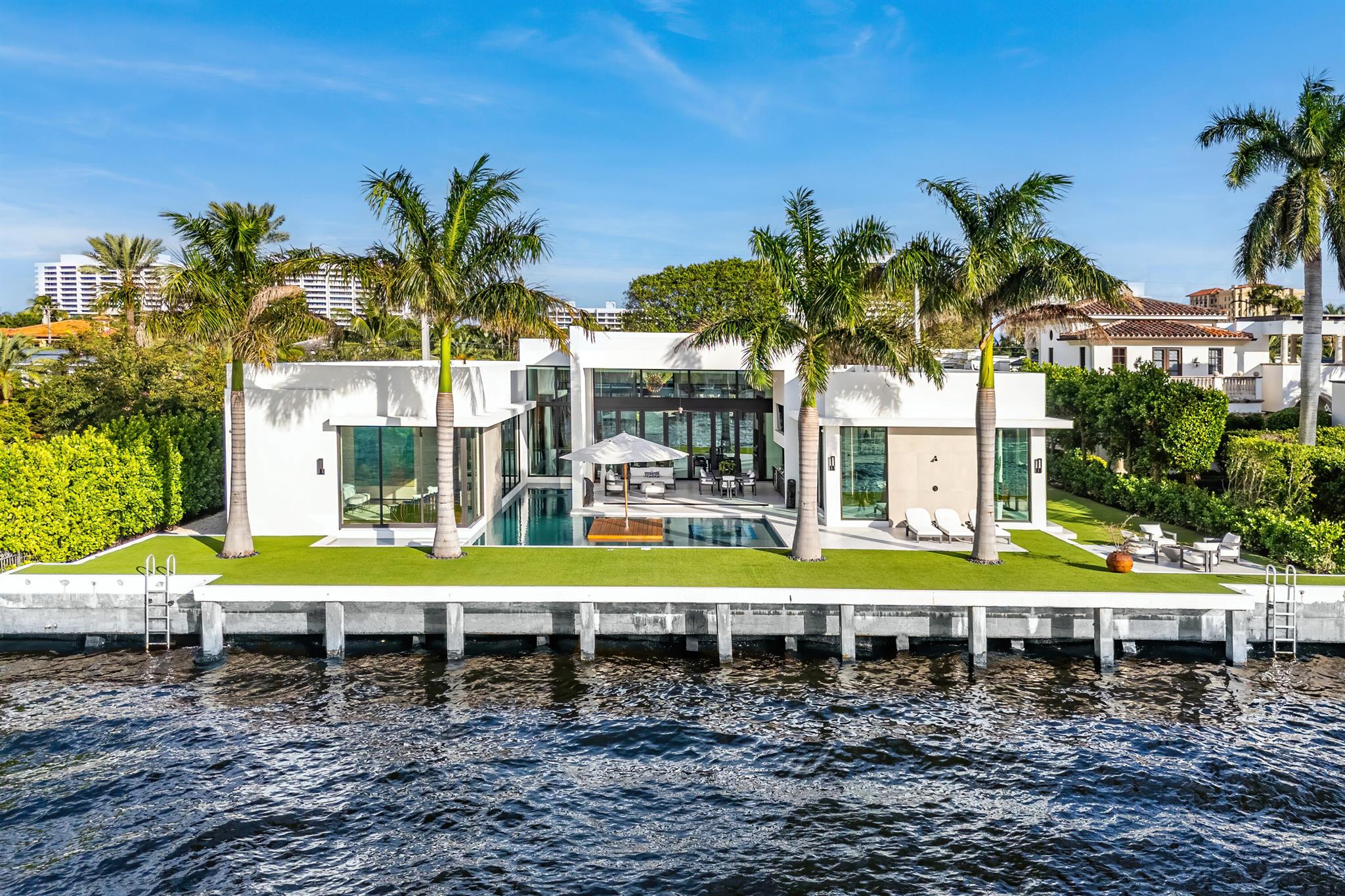 Introducing 1801 Spanish River Road - A Modern Seaside Masterpiece on the Intracoastal. This stunning, single-story estate combines sleek design with waterfront luxury, offering 109 feet of prime water frontage and sweeping views of Boca Raton's exclusive Intracoastal waterways. Step through the private, gated courtyard over a bridge flanked by serene reflecting ponds and arrive at a masterpiece encased in glass. The residence features sophisticated design elements throughout, including a grand 10-foot-tall pivot entry door, soaring ceilings, and a transparent 168-bottle wine wall. The great room dazzles with a backlit fireplace and a 26-foot-long Eurowall folding door that seamlessly connects indoor and outdoor living on the rear lanai. The custom Poggenpohl chef's kitchen caters to the most discerning tastes, while the master wing offers luxury and tranquility with corner pocketing-sliding-glass doors that frame breathtaking Intracoastal views and provide direct pool access via elegant stepping stones.

The estate's clubroom is an entertainer's dream, overlooking the Intracoastal with sliding glass walls that open to an inviting outdoor firepit lounge and pool area. This seamless indoor-outdoor transition extends the entertainment space, creating a perfect setting to enjoy waterfront sunsets in style.

Outdoors, the estate invites gracious, resort-style living. The lanai overlooks a patio and a wraparound lap pool with a champagne spa, oversized sun shelf, and a unique floating island, creating the ultimate relaxation and entertainment space. Additionally, the four-bay garage is a car connoisseur's dream, offering ample space for an exceptional collection.

Experience the coveted East Boca Raton lifestyle in the prestigious, non-HOA neighborhood of Spanish River Land. With easy access to the beach, Mizner Park, Boca Raton Resort & Beach Club, and Downtown Deerfield Beach, 1801 Spanish River Road is perfectly positioned to offer both luxury and convenience.