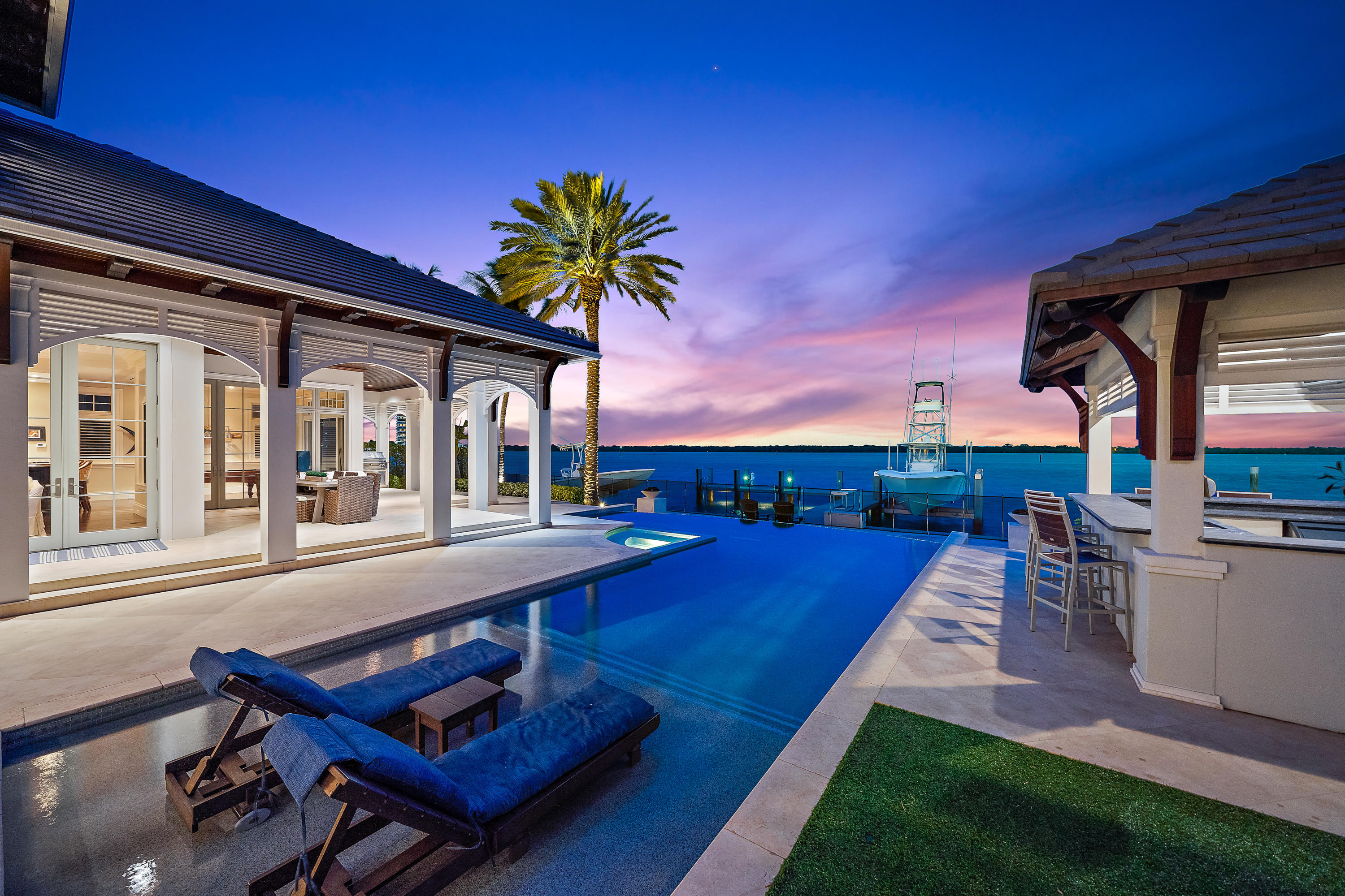 This waterfront estate designed by Randall Stofft and built by renowned builder Turtle Beach Construction is the definition of refined luxury living in one of the most desirable North Palm Beach neighborhoods. Stunning sunrises and sunsets over the wide water pour through oversized windows throughout the home, while its location across from MacArthur State Park offers nature views from all vantage points.  Immediately upon entering the grand two-story foyer, you will find an abundance of high-end features, such as the elegant Capiz shell chandelier, coffered ceilings, and custom millwork all of which add charm and sophistication to this magnificent home.  The welcoming foyer leads you directly into the bright airy living room with its exceptional wide water views, grand fireplace and adjacent formal dining room, complete with temperature-controlled walk-in wine cellar. The great room with wet bar and billiard table provides plenty of space to entertain in style, and opens to the gourmet kitchen, fit for even the most discerning of chefs. Replete with Wolf, Sub-Zero, Bosch and Miele-- top of the line brand appliances, built-in cabinetry with coffee/espresso maker, a center island, and breakfast nook, the expansive kitchen area is also the perfect setting for more intimate gatherings and meals. Upstairs, the master ensuite is a grand escape from the rest of the home with views of the water from its covered balcony and a spa-like master bath with stunning marble countertops, and soaking tub.  Also upstairs are the 2nd and 3rd bedroom suites with additional living room space, as well as a complete fitness center with state-of-the-art equipment. Step out to the rear veranda and find an exquisite infinity saltwater-heated pool, spa, and a built-in kitchen and bar. The covered seating area looking out to intercoastal waters is the perfect place to spend an evening outdoors. The property also has a 2-slip dock with boat lifts; perfect for housing watercraft, whether it's for taking in a sunset cruise or enjoying a day of sport fishing. There is no fixed bridge and the Palm Beach Inlet is only minutes by boat. With many other unique features included, proximity to Lakeside Park and the newly renovated North Palm Beach Country Club, this home is Florida waterfront living at its finest.