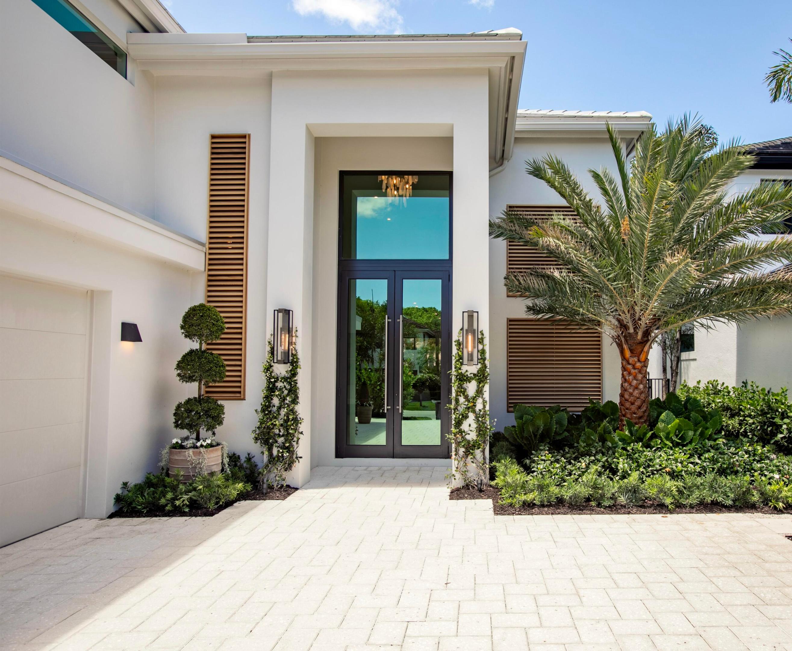 In exclusive Frenchman's Creek Country Club, this completely reimagined residence was taken down to the studs and redesigned by Pear Design Build. The 4BR/3.2 BA home features a dramatic two-story atrium, floating white oak staircase with illuminated treads, custom fluted-glass pivot doors, and soaring open living spaces designed with a warm island-inspired aesthetic. From the moment you enter, the home draws your eye through expansive living spaces with 19' ceilings, to the showpiece kitchen featuring rift-sawn white oak cabinetry, honed Brazilian granite, premium Thermador appliances, and 10-foot-high doors and windows overlooking the private resort-style backyard.  Designed for seamless indoor-outdoor living, the exterior spaces include a new saltwater pool, spa, outdoor kitchen, and lush tropical landscaping curated for privacy and entertaining. Additional highlights include a signature Family Suite, library retreat, curated designer lighting, all new impact-rated windows and doors, garage doors, and a new roof. Full furniture package available.