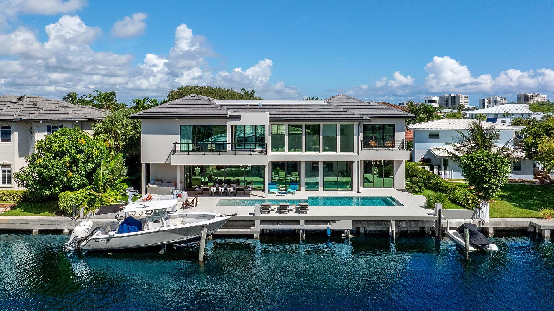 Like-new modern waterfront estate in the coveted Lake Rogers community of East Boca Raton. Built in 2024 by Elysee Homes, this exceptional residence offers 90 feet on the water with direct Intracoastal views. Elegant herringbone wood floors, designer lighting, and a sleek chef's kitchen with Wolf gas range and integrated appliances define the interiors. Expansive pocket sliding glass doors create seamless indoor-outdoor living with pool and entertaining areas. Includes a first-floor guest suite and club room plus a stunning primary suite with dual custom closets, spa-inspired bath, and panoramic water views. Moments from the beach and close to Downtown Boca, Delray, international and private airports. A rare opportunity and property offering a lifestyle second to none. Positioned on 90 feet of prime waterfront, the home enjoys breathtaking direct Intracoastal views and an effortless connection to the outdoors. Expansive pocket sliding glass doors vanish completely, blending the refined interiors with a resort-style exterior featuring a stunning pool, summer kitchen, covered entertaining areas, and a private dock.   Inside, timeless sophistication meets contemporary design through herringbone wood flooring, custom lighting, and an open layout ideal for elegant entertaining. The chef's kitchen showcases custom millwork, modern countertops, integrated top-tier appliances, and a Wolf gas range, designed for those who appreciate style and performance. Two car garage with electric vehicle charger plus decorative driveway allow for ample parking.   The main level includes a guest suite and a club room, while the upper level is anchored by a spectacular primary suite with dual custom closets, a spa-inspired bath, and sweeping Intracoastal views. Every detail has been thoughtfully curated, from the architectural lines to the layered textures and lighting, creating a home that is as comfortable as it is captivating.   Ideally located moments from the beach via Spanish River Boulevard, and just minutes from Downtown Boca Raton and Delray Beach, residents enjoy quick access to world-class dining, shopping, and entertainment. The home is also conveniently close to both private and international airports, offering a lifestyle of elegance and accessibility.   This exceptional property presents a rare opportunity to own a newly built waterfront estate in one of Boca Raton's most desirable neighborhoods - a home that truly delivers a lifestyle second to none.  All images and visual materials associated with this property, including AI generated images, virtually staged photos, edited images, artist conceptual renderings, maps, site plans, floor plans, and other graphics, are provided solely for illustrative purposes. These representations may not accurately reflect current conditions and are subject to change without notice. No representations or warranties are made regarding the accuracy or completeness of these visual materials. Buyers should not rely solely on these materials and are responsible for independently verifying all property details.