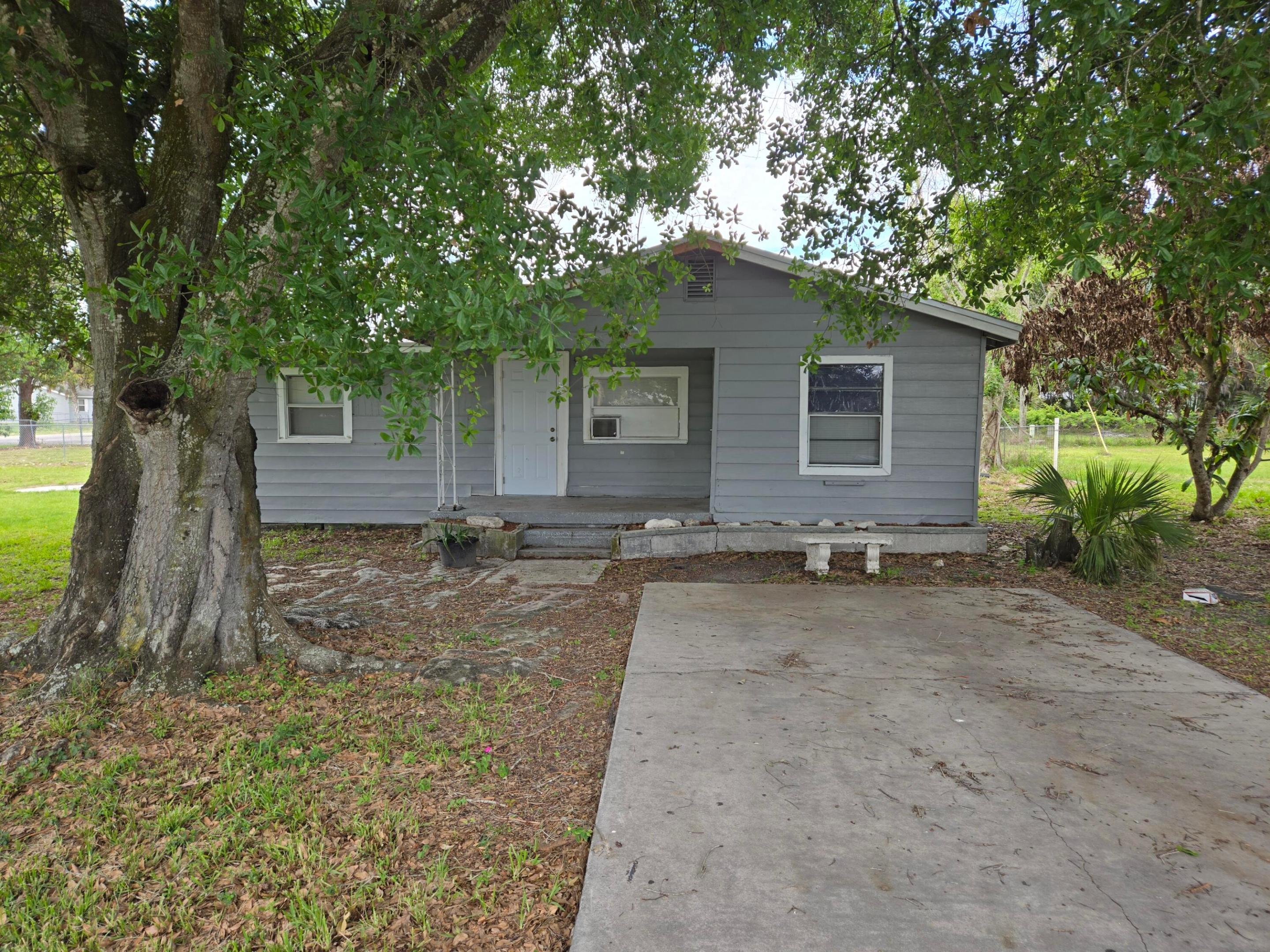 **Charming Okeechobee House on Oversized Corner Lot!**  Discover the perfect blend of classic charm and modern convenience in this original Okeechobee Home! Nestled on a spacious corner lot adorned with majestic shade trees, this home offers endless potential for expansion, including room for an in-law suite. Step inside to find a partially updated interior featuring NEW hardwood flooring and a contemporary bathroom (2023). The updated kitchen is ready for your culinary creations. With a NEW roof (2024) and fresh siding on the back base, this home is poised for easy living. Ideal for families or as a savvy investment opportunity, this property places you right in the heart of Okeechobee. Enjoy the convenience of being within walking distance to downtown shopping, dining, and entertainment. Explore friendly attractions like Flagler Park, and take advantage of the nearby parks and trails for outdoor recreation. Go fishing at Lake Okeechobee.  With city utilities and paved roads, this is a fantastic find in a city known for its Southern hospitality. This is Priced to sell quickly—don't miss your chance to make this delightful house your own! Call today to schedule your private showing before it's gone!