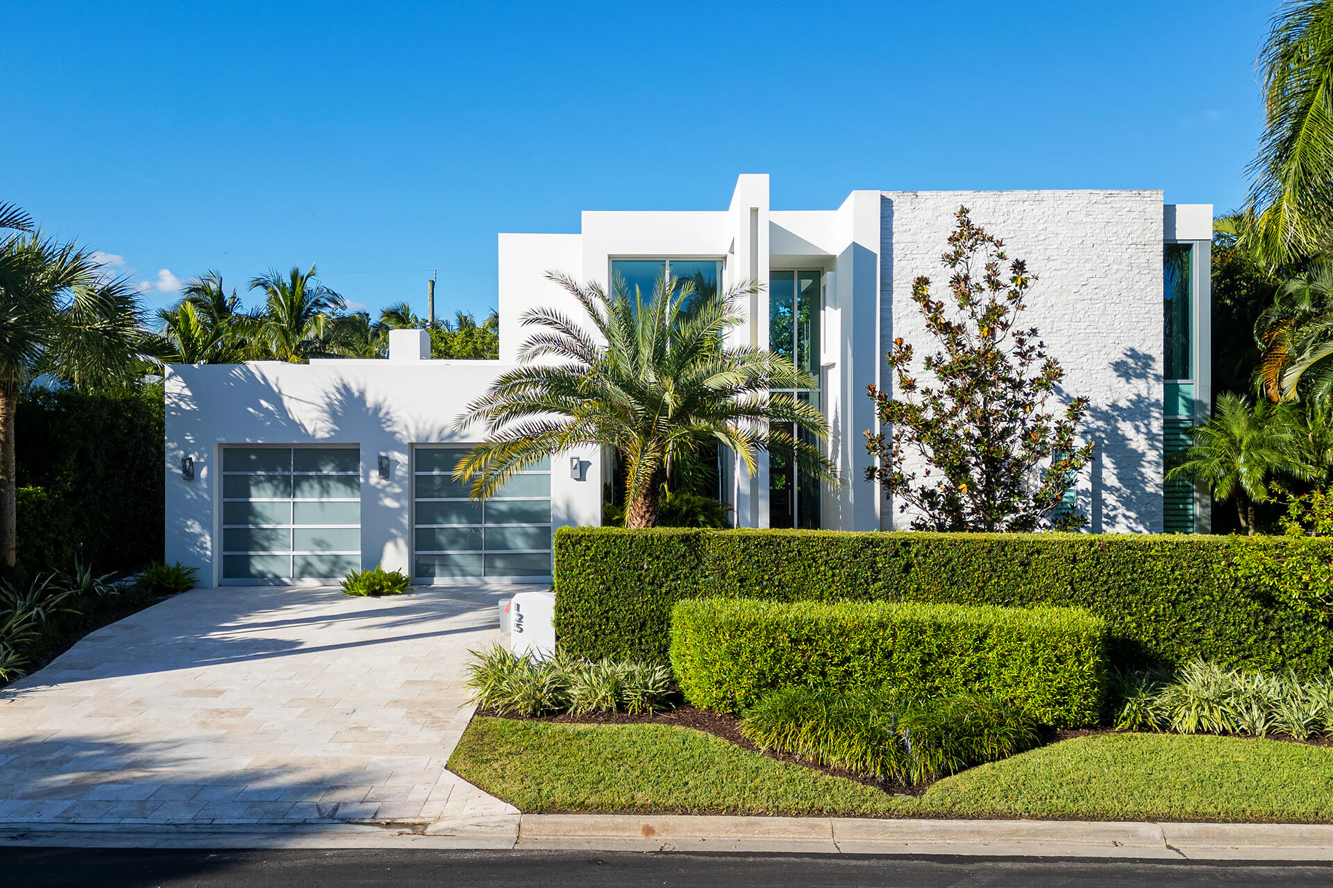 This stunning contemporary two-story home is perfectly positioned on the 100 block of Churchill Road, second property in from the Intracoastal Waterway in West Palm Beach.   Custom built in 2016 by the current owner, the home offers an ideal canvas for a variety of tastes and lifestyles.  With sleek, modern architecture the residence boasts a first-floor primary suite, ensuring convenience and luxury. High ceilings and expansive windows fill the space with natural light, enhancing the open, airy atmosphere.
Outdoors, a pool and large terrace awaits for year-round enjoyment, while the spacious backyard and patio provide the ultimate setting for entertaining, lounging, or dining al fresco. Privacy hedging surrounds the property, creating a sanctuary for relaxation and tranquility.