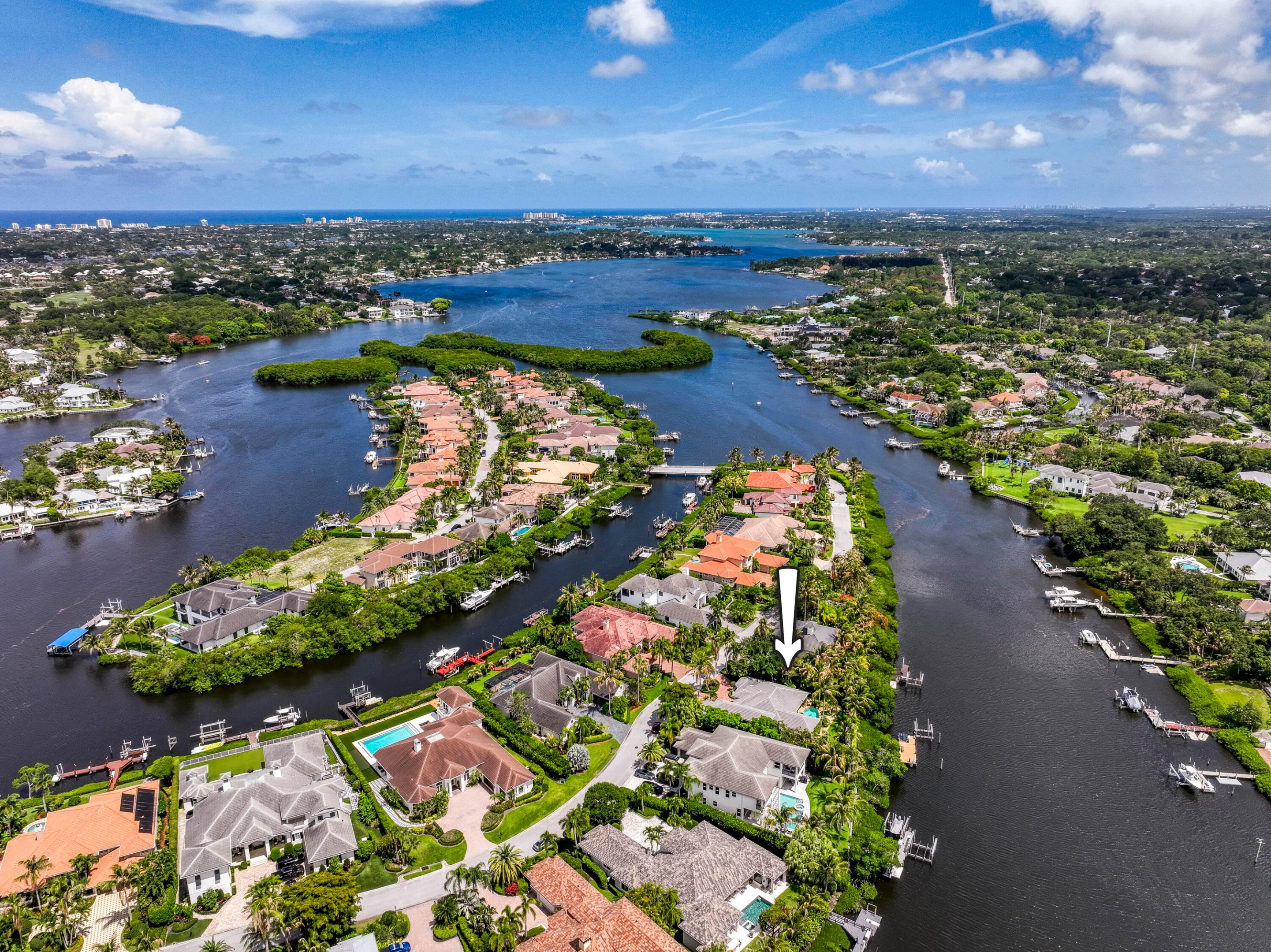 Nestled within the exclusive gated community of Islands of Jupiter, this beautifully updated waterfront estate offers 105 feet of frontage on the scenic Loxahatchee River. Meticulously maintained, the 5-bedroom, 3.5-bath residence blends timeless elegance with modern comfort. The first-floor primary suite serves as a private retreat with tranquil garden and river views, rich wood flooring, and a renovated spa-inspired bath featuring marble finishes and a freestanding Victoria & Albert soaking tub. Recent improvements include a flat tile roof, impact windows and doors, and a 38kW Generac whole-house generator. Outdoors, lush tropical landscaping creates a private resort-style setting centered around a sparkling pool and spa overlooking the river. Boating enthusiasts will appreciate the  private dock with an upgraded 15,000-pound lift. The expansive tiki hut, complete with a summer kitchen, built-in grill, and pull-up bar, provides the perfect backdrop for waterfront entertaining and the ultimate Jupiter riverfront lifestyle.