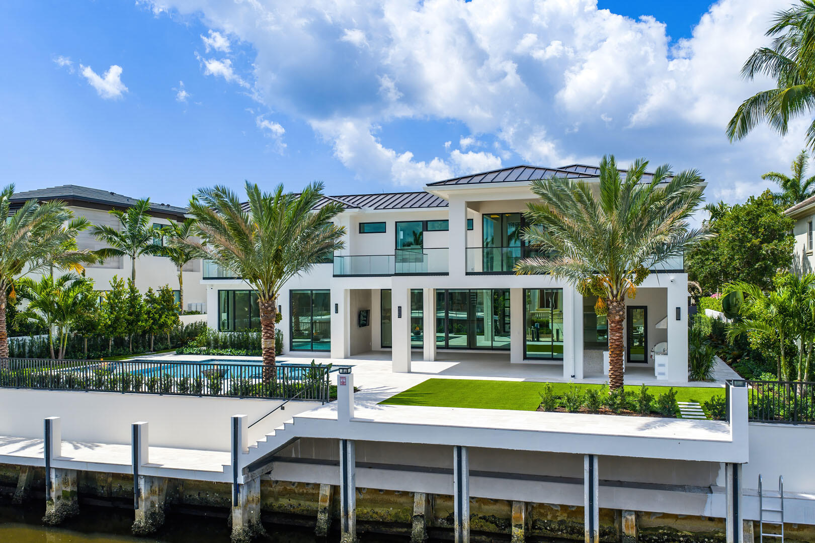 Experience unparalleled luxury in this brand-new waterfront estate in the prestigious Royal Palm Yacht & Country Club. Designed by The Benedict Bullock Group and masterfully built by Hanna Homes, this residence offers over 10,000 square feet of exquisitely crafted living space, seamlessly blending modern sophistication with timeless elegance. A grand entryway leads to expansive living areas, where walls of glass frame breathtaking water views. The gourmet kitchen, complemented by an attached service kitchen, is a chef's dream, outfitted with top-tier appliances and custom finishes. A sophisticated club room with a full bar, a spacious office, and a state-of-the-art gym elevate the home's lifestyle appeal. Seven lavish bedroom suites include an extraordinary primary retreat with dual spa-inspired baths and dressing rooms. Two VIP suites provide luxurious accommodations for guests. Crestron smart home technology, an elevator, and a whole-house generator ensure effortless living. Step outside to a resort-style backyard designed for both relaxation and grand entertaining, featuring a covered loggia with a fully equipped summer kitchen, a striking pool and spa, and a private dock with direct Intracoastal access. This remarkable new construction offers an unrivaled blend of comfort, technology, and waterfront living in one of South Florida's most exclusive enclaves.  The buyer is responsible for documentary stamp taxes on the deed and title insurance.