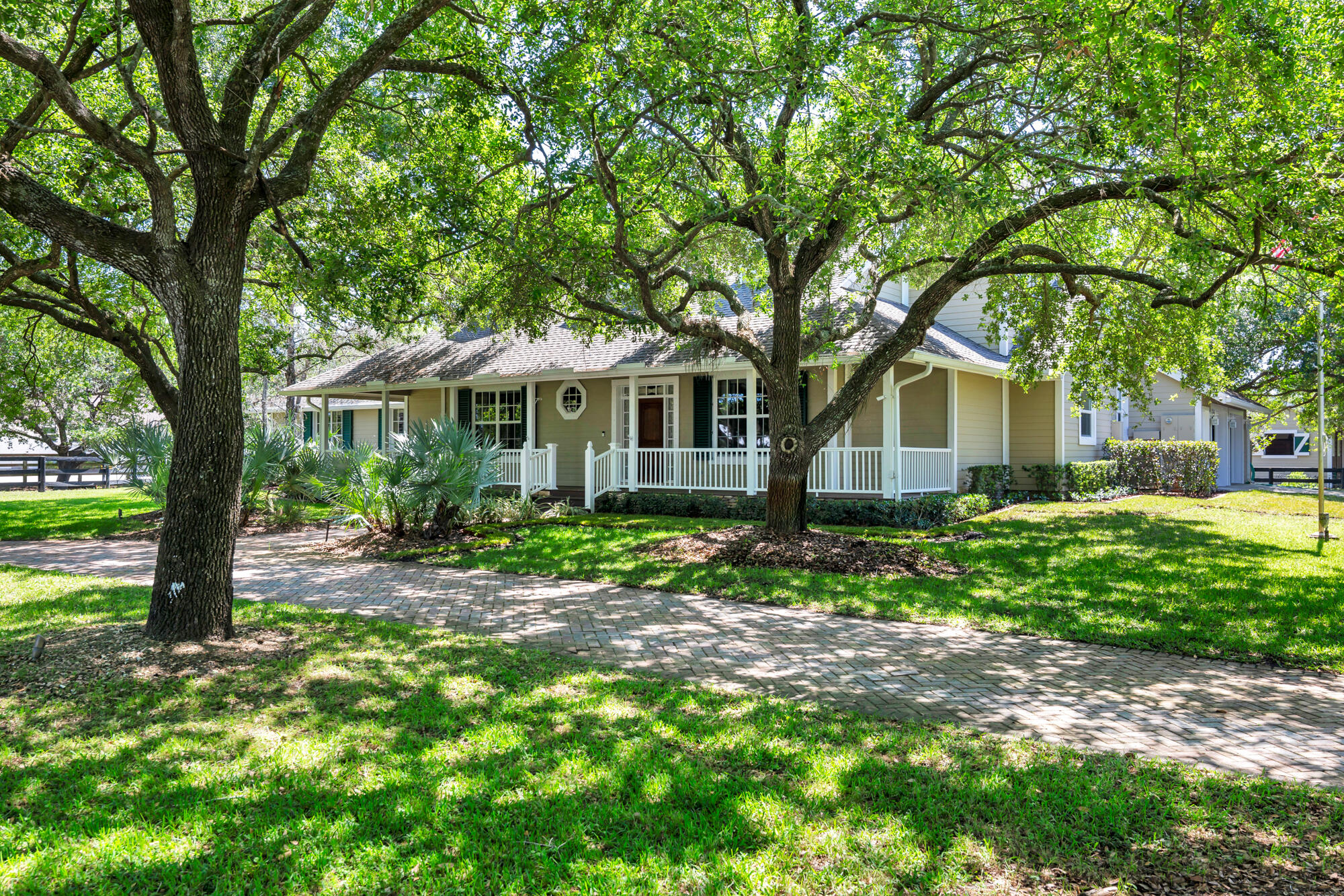 First time on market! Property features 2 barns with a total of 16 stalls all on 6 acres in the heart of Wellington's equestrian community. Stonegate Farms is an exceptional equestrian estate within hacking distance to Wellington International, home of the world-renowned Winter Equestrian Festival.  Framed by majestic 40-year old Live Oak trees, the property exudes charm and tranquility. Designed with both horse and rider in mind, the farm features 9 oversized grass paddocks, each approximately ¼ acre, offering ample turnout on lush grass and plenty of shade.  The custom-built residence has 5 bedrooms and 4 baths thoughtfully designed for everyday living. At the heart of the home is a spacious great room defined by soaring vaulted ceilings capped with a tongue and groove cypress ceiling. The light and bright eat-in kitchen flows seamlessly into the great room and features a gas range and large walk-in pantry. The master bedroom overlooks the pool area and has a large walk-in closet and master bath with his and her vanities. A guest bedroom across the hall overlooks the property's majestic oak hammock and is complemented by a beautifully finished marble tiled bathroom.  A hallway leads to a large, rustic media room boasting 1,000 year old river-recovered pecky cypress ceiling, walnut wood flooring and a double-sided Alabama fieldstone fireplace featuring a 1,000 year-old river recovered cypress mantle. A large office space is situated on the other side of the fireplace. At the back of the house is a beach-inspired secondary master bedroom with cabana bath that overlook and open onto the pool area, making an ideal retreat for guests or multigenerational living. Upstairs are two more bedrooms with walk-in closets and a shared bathroom and an office overlooking the great room below. All windows in the house are hurricane impact glass. Designed for indoor-outdoor living, French doors in the great room and primary master bedroom open onto the covered patio and resort-style pool area. The 38' x 18' saltwater pool with integrated spa are accented with natural stonework inspired by the streams of Tennessee, creating a serene and luxurious outdoor escape. Behind the main residence is a charming four-stall barn and three paddocks. At the center of the property are four 1/4 acre grass paddocks and a one-acre grass riding field. The center of the grass riding field is home to a massive 40-year-old Live Oak tree unique to all of Wellington in its size and beauty.  On the west side of the property with a separate driveway is a magnificent 12-stall center isle show barn, complete with a well-appointed two bedroom/two bath apartment with hurricane impact windows throughout, office, grooming stall, feed room, airconditioned tack room, laundry room and half bath. Behind the barn are 3 outdoor wash racks and a slab with hookup for a treadmill. The 12-stall barn overlooks an all-weather 115' x 207' riding ring and is surrounded by mature Live Oak and Maple trees and two oversize grass paddocks. A large 2-bay storage building offers plenty of room to store hay, shavings, jumps and the tractor and ring drag. The farm has direct access to the bridle path and is a short hack to the Wellington International show grounds.