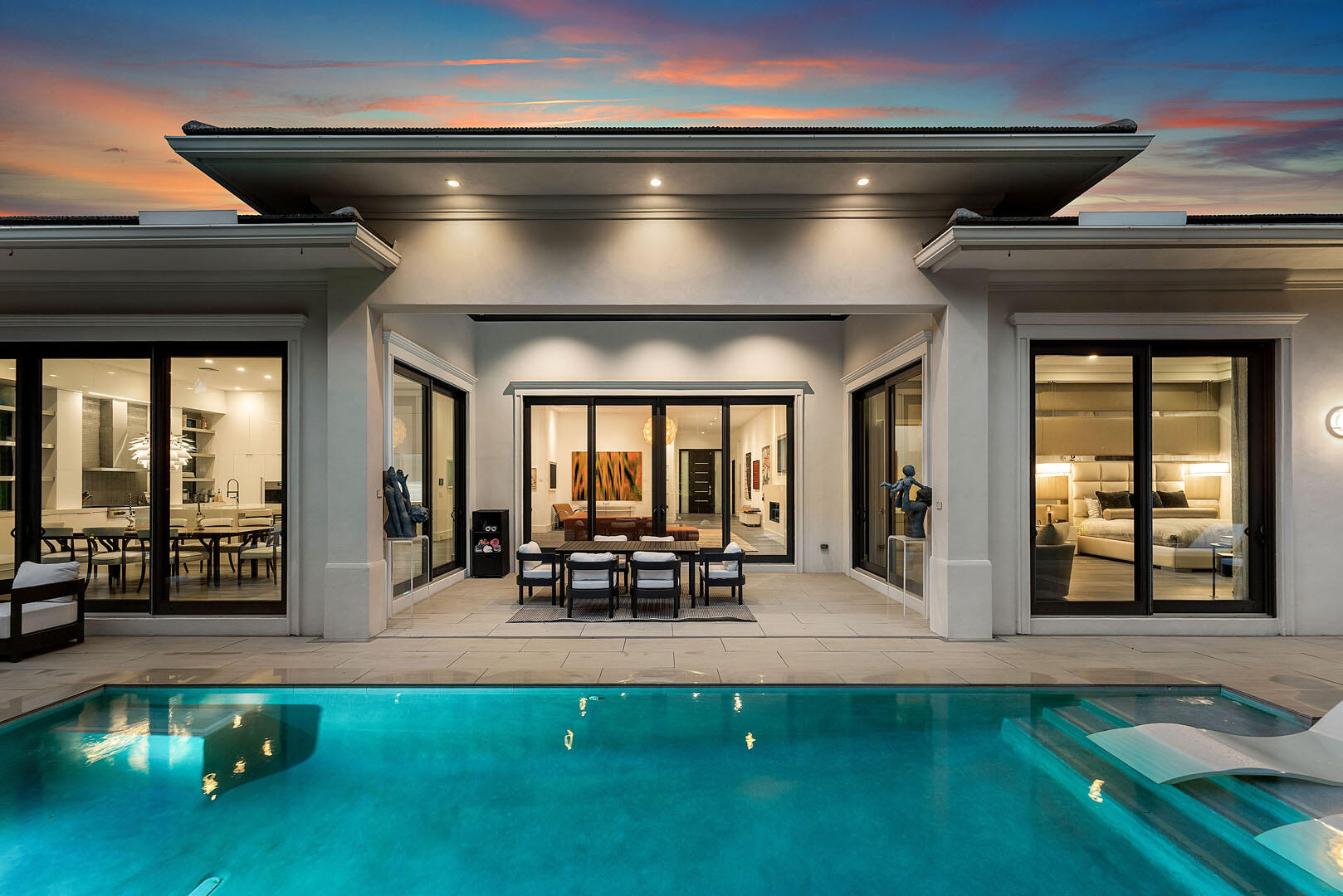 A single-story masterpiece unfolds in the prestigious Royal Palm Yacht & Country Club. Modern elegance meets effortless living across 4,500 square feet. Four spacious bedrooms are tucked within a home defined by 14-foot ceilings. The open, light-filled design feels grand yet intimate. Every detail is curated for ease and sophistication. Technology and comfort blend—Control4 orchestrates lighting, music, security, and ambiance with a touch.  At the home's center, a striking modern kitchen commands attention with custom cabinetry, a walk-in pantry, two dishwashers, and a professional-grade gas range. A gas fireplace brings warmth and atmosphere to living and dining spaces that flow together, hosting gatherings or quiet evenings.    At the rear, floor-to-ceiling glass doors erase the line between indoors and the lush, manicured landscape—an ever-changing scene of light, greenery, and serenity. This is more than a home—it's a private retreat where modern luxury is truly experienced.