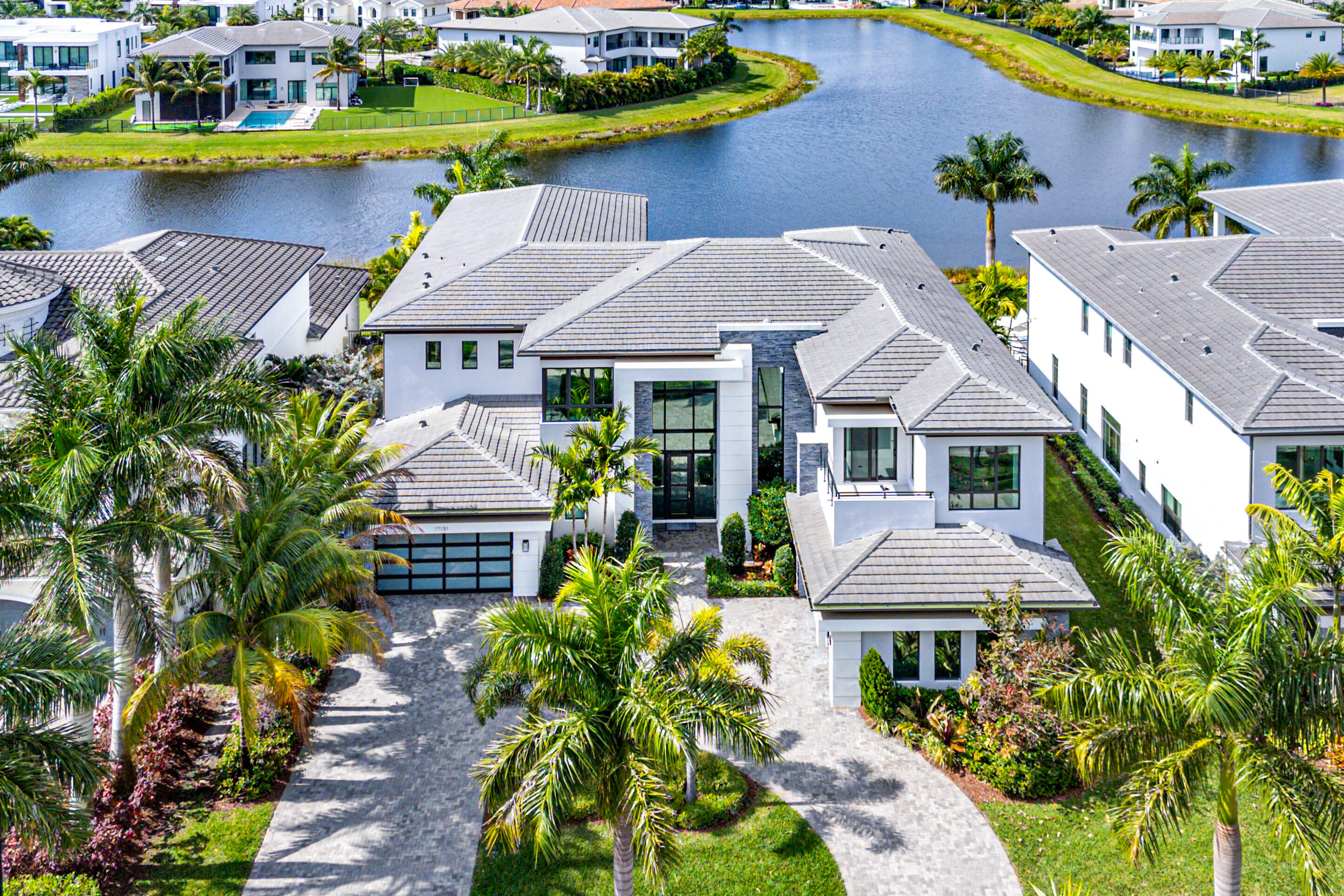 A Masterpiece in the Estate Section of Boca Bridges' Most Coveted Lakefront

Boca Bridges — complete with lavish amenities and elite security — provides the prestigious backdrop for this meticulously customized Vanderbilt Grande Contemporary. Perfectly positioned on a sprawling, premier long-lake lot, this estate captures breathtaking sunset views and delivers inviting resort-style allure to the luxury residential experience.

Spanning over 11,000 total square feet with 8,179 square feet of living space, the exquisitely designed layout offers six ensuite bedrooms, a powder room, a cabana bath, a warm and inviting family room, a loft with private balcony, and a 4-car garage. Inside, striking design elements include a glass-railed staircase, designer millwork, and a sleek gas fireplace anchoring the main living area. A private lounge, fully equipped home theater, and whole-house generator elevate the lifestyle experience.

The state-of-the-art gourmet kitchen showcases premium appliances, including a custom hood, 60" Sub-Zero refrigerator/freezer, 48" Wolf range, and a built-in banquette. Light-filled spaces bring the outdoors in, creating a seamless flow to the backyard retreat  a heated saltwater pool with spa, covered loggia, summer kitchen, and turfed yard, all set against sweeping water views.

The prestigious Boca Bridges community offers residents an unparalleled lifestyle, with a 27,000 sq. ft. clubhouse featuring an elegant lounge with bar, a card room, a game room, and an indoor sports area. First-class amenities include fitness facilities, swimming pools, tennis and pickleball courts, and activities for all ages, rivaling the finest resorts.