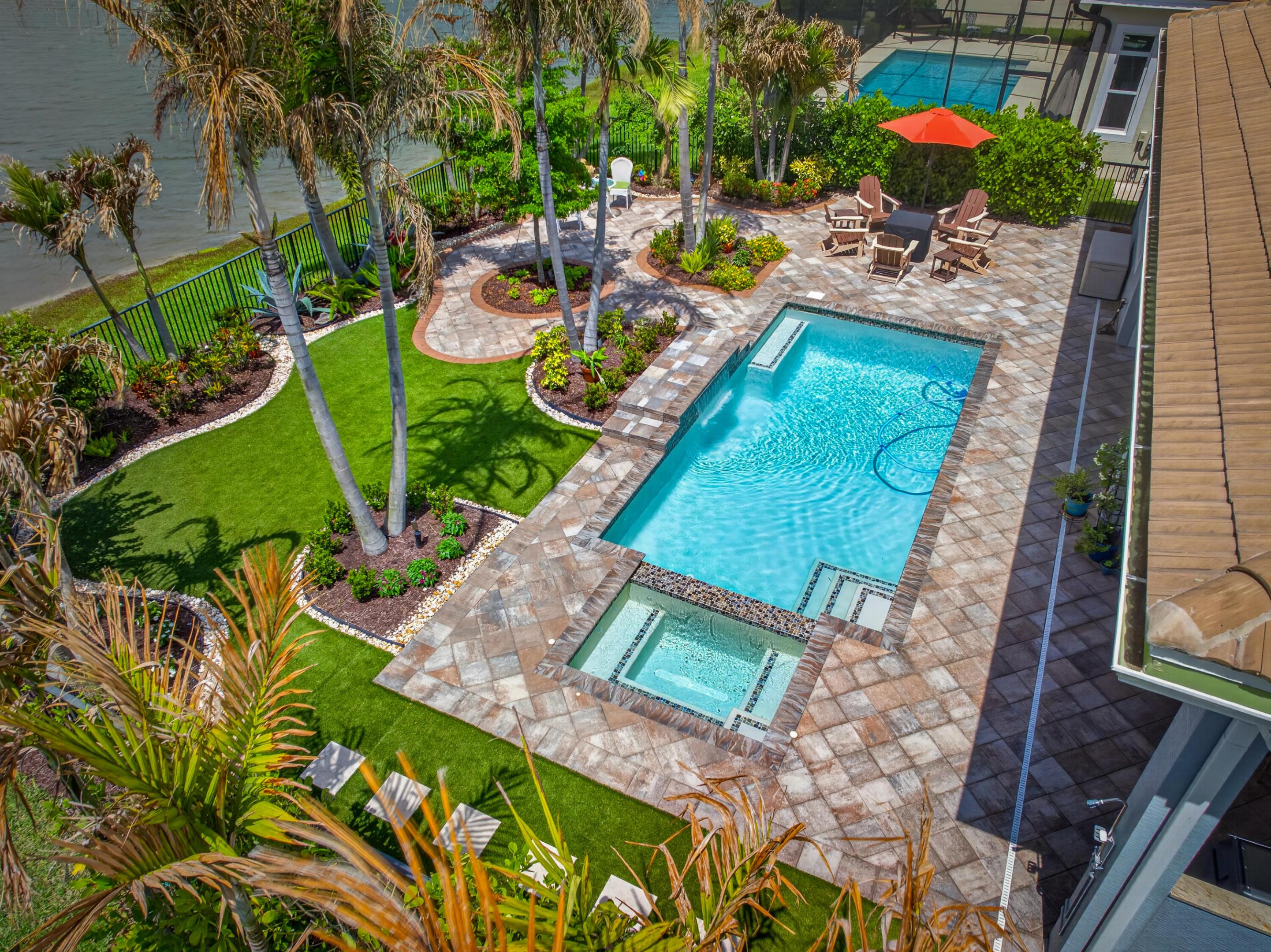 GORGEOUS LANDSCAPED BACKYARD w/artificial turf trees shrubs flowering beds paver & landscape lighting, complemented by an 11' x 29' pool and spa wit, summer kitchen with privacy wall, outdoor hot water shower, and fully fenced oversized yard. Interior upgrades include gourmet kitchen with wall oven and stainless steel chimney hood, quartz countertop drop zone, and solid-core interior doors. Primary bedroom features cabana door with direct lanai access. Additional features include driveway, lanai, and yard pavers resealed in 2025, three-car garage with epoxy floor coating, whole-house water filtration and conditioning system, two rear hard-wired surround sound speakers in great room ceiling, Pottery Barn light fixtures incl foyer chandelier, plantation shutters & additional win treatments
