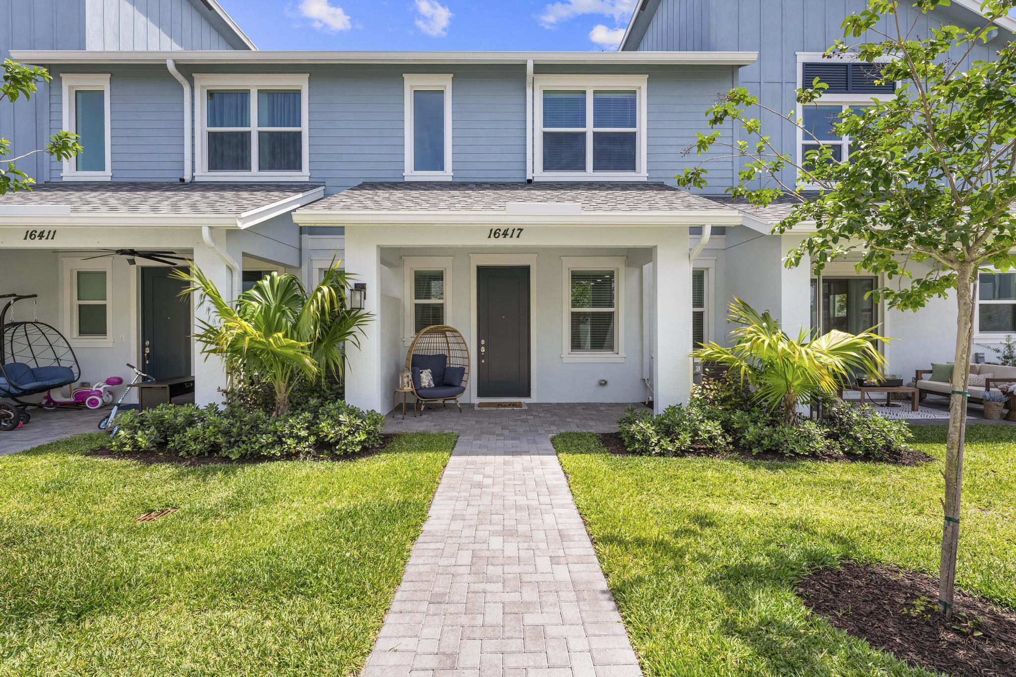 Welcome to this stunning newer construction 3-bedroom, 2.5-bathroom townhouse offering modern design, quality finishes, and functional living throughout. This beautifully built home features an attached 2-car garage with a hurricane impact garage door and an impressive 8-foot entry door.  Inside, enjoy soaring high ceilings, recessed high-hat lighting, and tile flooring throughout the main living areas. The open-concept kitchen is designed for both style and convenience with granite countertops, stainless steel appliances, and ample cabinet space. A convenient half bath is located downstairs for guests. Wood stairs lead to the second floor, where you'll find high ceilings and elegant wood-look tile flooring throughout. The spacious primary suite features dual sinks, a walk-in closet, and a large walk-in shower. The upstairs laundry room includes built-in cabinets for additional storage and convenience.  All appliances are 2025 models. Relax on the covered front porch and enjoy additional guest parking located directly on the street. This move-in ready new build offers the perfect combination of modern upgrades, comfort, and low-maintenance living.