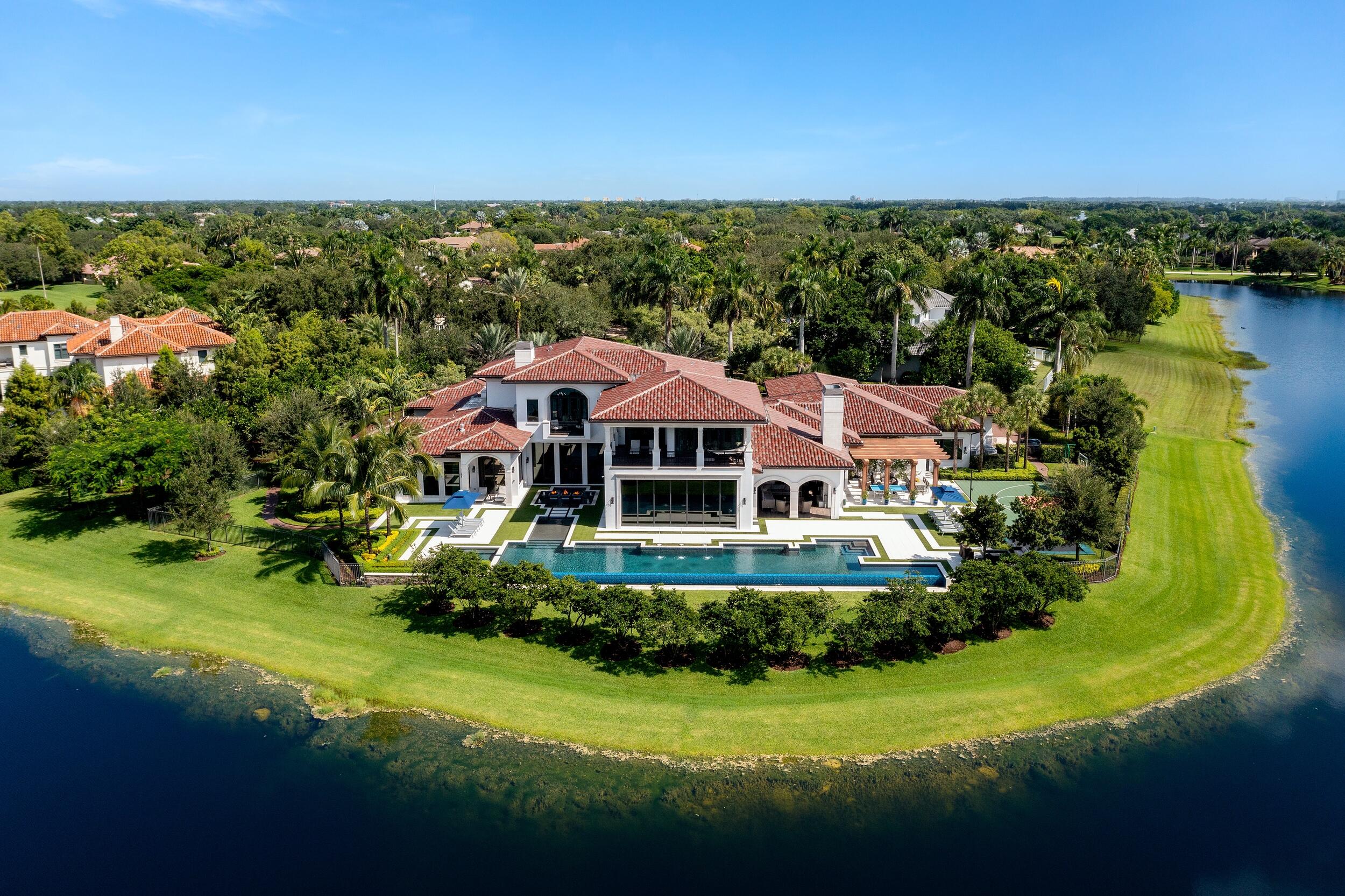 The worlds of chic contemporary design and resort-style comfort find common ground amid a prestigious gated community in Weston. Windmill Ranch Estates, constructed around the waterways that distinguish the landscape in this coveted part of west Broward County, provides an idyllic setting for this beautifully rendered seven-bedroom sanctuary by renowned architect Randall Stofft. Designed on a canvas bathed in brilliant, invigorating whites—like the custom cabinetry in the chef's kitchen and master bathroom (one of eight full baths to go with three half-baths), or the Turkish Carrara marble flooring in the dining area and formal living room—and complemented by rustic earth tones, the layout carries a thread of clean sophistication throughout its two floors. Accents and interior touches by Decorators Unlimited add to the splendor of a home that's being sold fully furnished. It's a property, cast on a more than 1.5-acre lot, that's built for entertaining as evidenced by the 2,000 square feet of family room/kitchen living spacepart of a sprawling interior that encompasses over 12,000 square feet. Other indoor highlights include Savant Smart Home technology (with automated control of everything from lighting and audio to fans, security, and the thermostat); a commercial grade elevator; a butler's pantry; a state-of-the-art Cinematech designed movie theatre which seats 24 people; authentic Jerusalem stone; state-of-the-art appliances in the double-island kitchen; a home gym; and a surround-sound system comprised of some 100 combined indoor/outdoor speakers. The exterior is an oasis unto itself, an ode to the good life anchored by a striking 93-foot-long heated infinity edge pool, as well as an in-ground spa with room for 12 people. The multipurpose sports court features a glass-backboard basketball hoop, but it's also designed for pickleball and other activities. Custom made, in ground trampoline - great for all ages!  The spacious outdoor setting also boasts a summer kitchen and dining area; a separate entertainment space, with a fireplace and flat-screen TV; and a dramatic fountain just off the pool with three stone-filled square fire bowls. Residence has a four car garage with the capability of installing car lifts - which totals 8.