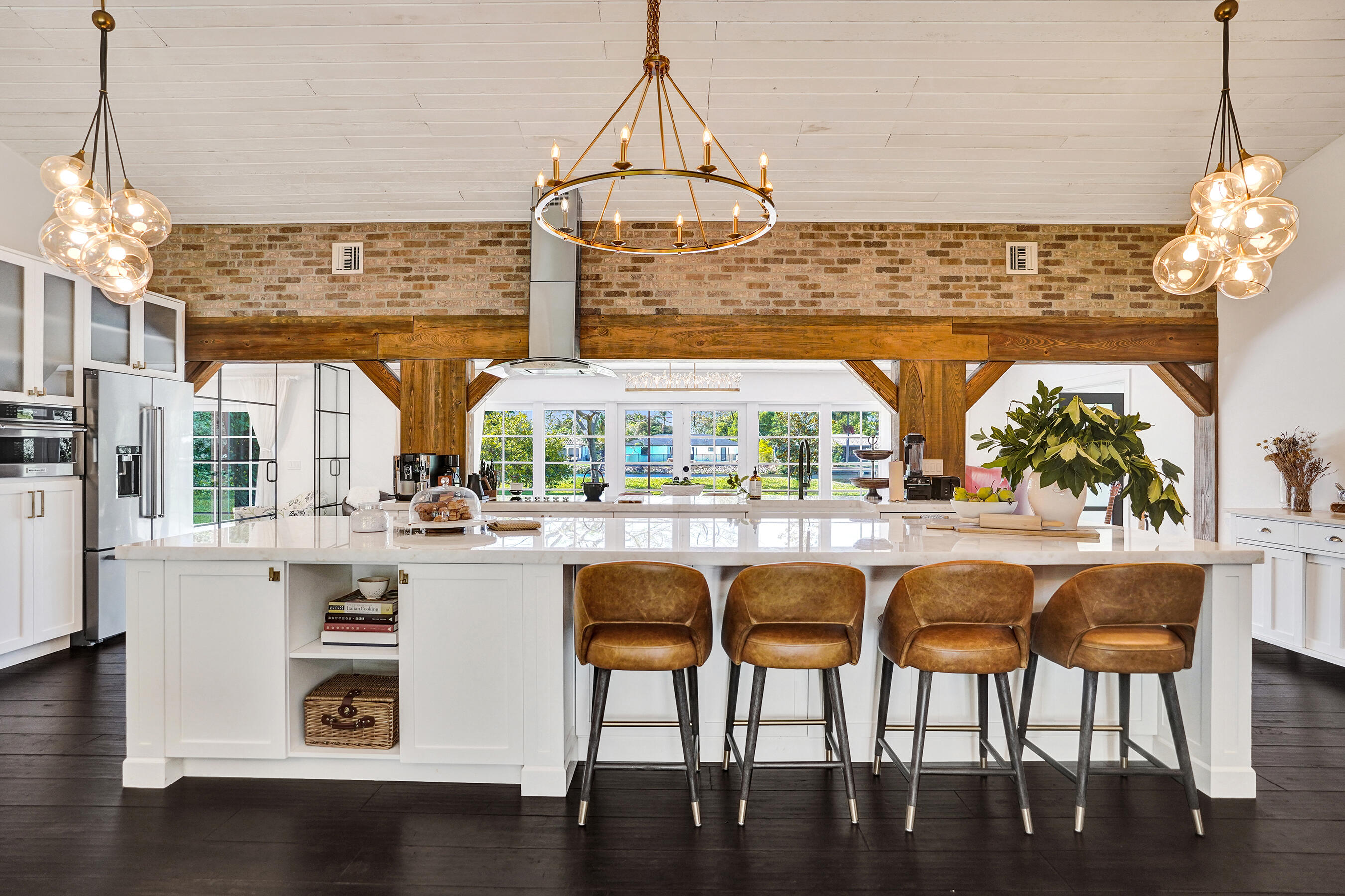 * NEW Roof being installed now* Some homes are built. This one was crafted. By hand, with copper and  marble and reclaimed timber sourced piece by piece. Tucked along a quiet canal in Hidden Valley, NE Boca Raton, the house sits twelve feet above grade with seventy-five feet of waterfront. Steel framed glass walls catch the light. Reclaimed wood beams cross  a kitchen anchored by a brass wagon wheel chandelier, an oversized marble island, and reclaimed brick. Cypress wood cabinetry with Restoration Hardware finishes, built by hand. A custom suspended staircase rises to a secret hideaway loft above. The kind of room  that becomes the favorite room without anyone announcing it. The master bath reads like a small spa. Copper rainfall fixtures. A freestanding clawfoot tub. (See Supplement) Herringbone Carrara marble. Signature Hardware fixtures throughout, chosen one piece at a time across every  bath in the home. A sunroom with floor to ceiling glass overlooks the canal. Lutron  smart lighting learns the rooms. A seven-stage reverse osmosis system  serves the tap. The bones are quietly serious: Carrier 3.5T HVAC  installed this year, whole-home hurricane impact windows and garage  door, epoxy garage floor with a marble finish, marble baseboards, EV  charger, finished and insulated. Flood Zone X, LOMA confirmed, no  mandatory flood insurance. No HOA. A-rated Calusa Elementary, magnet  middle, and magnet high. Four bedrooms, a glass enclosed office, and the secret hideaway loft  upstairs. Substantially renovated. Out back, a travertine patio opens to a lawn that runs to the water's edge. Add a private dock and the seventy-five feet of canal frontage  becomes a launching point for paddleboard mornings, jet ski runs,  weekend fishing, and small boat access. A Vizcaya-inspired landscape  design shades the lot with mature Meyer lemon, Hass avocado, mango,  and magnolia. This is not a contractor build. This is one person's masterwork.