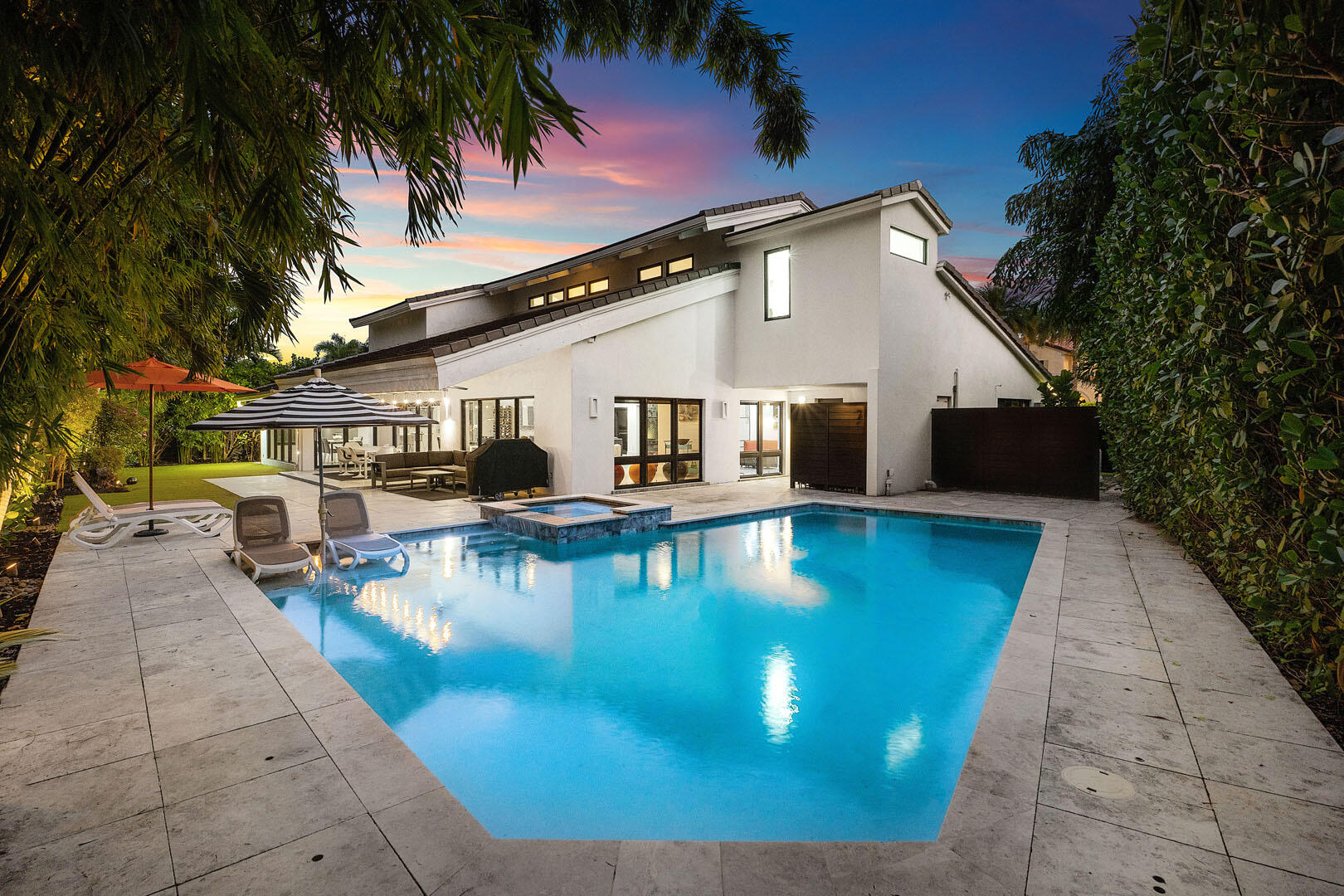 A refreshed two-story mid-century modern residence, this home is defined by dramatic vaulted wood ceilings, warm architectural character, and an effortless sense of style across just over 4,000 square feet of living space. Designed for both everyday comfort and elevated entertaining, the layout offers four spacious bedrooms and four-and-a-half beautifully appointed baths. At the heart of the home, a gourmet eat-in kitchen features a striking center island and premium appliances, creating a natural gathering place for family and guests alike. A glass-enclosed study overlooks the shimmering pool, offering a serene workspace framed by views of the backyard oasis. Step outside to a private retreat where a custom heated pool and spa invite year-round enjoyment, complemented by an outdoor shower and low-maintenance turf landscaping. The covered patio is perfectly arranged for al fresco dining and relaxed lounge seating, delivering the ideal indoor-outdoor lifestyle. The primary suite is a true sanctuary, complete with a spa-inspired bath and dual walk-in closets. Additional highlights include natural gas service, a generator, and impact glass throughout providing comfort, security, and peace of mind in a residence that feels both timeless and perfectly updated.