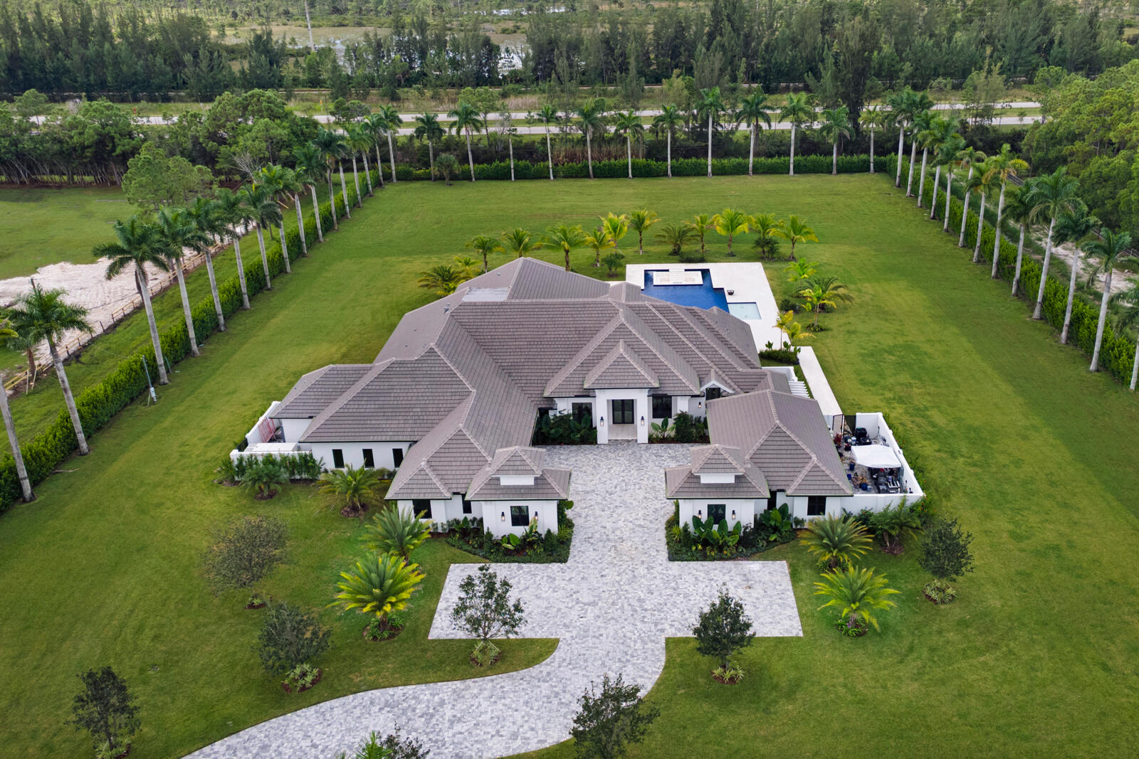 Welcome to this brand-new estate in the coveted equestrian community of Caloosa. Set on 5 private acres, this stunning residence offers over 6,000 square feet of living space with 4 bedrooms, 4 full and 2 half baths, plus an office, gym, and state-of-the-art movie theater. The heart of the home is an oversized chef's kitchen featuring high-end appliances, a spacious walk-in pantry, and elegant finishes designed for both entertaining and everyday living. Expansive living areas flow seamlessly outdoors to a resort-style pool with spa, sunken fire pit, and generous patio space with summer kitchen, perfect for gathering. Car enthusiasts will appreciate the attached 4-car garage, and additional detached 2-car garage, while those seeking wellness and recreation will love the private gym and media amenities. With soaring ceilings, impact windows, and refined architectural details throughout, every inch of this custom home has been crafted with luxury and function in mind. Enjoy the peace, space, and natural beauty of Caloosa with miles of riding trails and a true sense of privacyall just a short drive to Palm Beach Gardens, world-class golf, dining, and beaches.