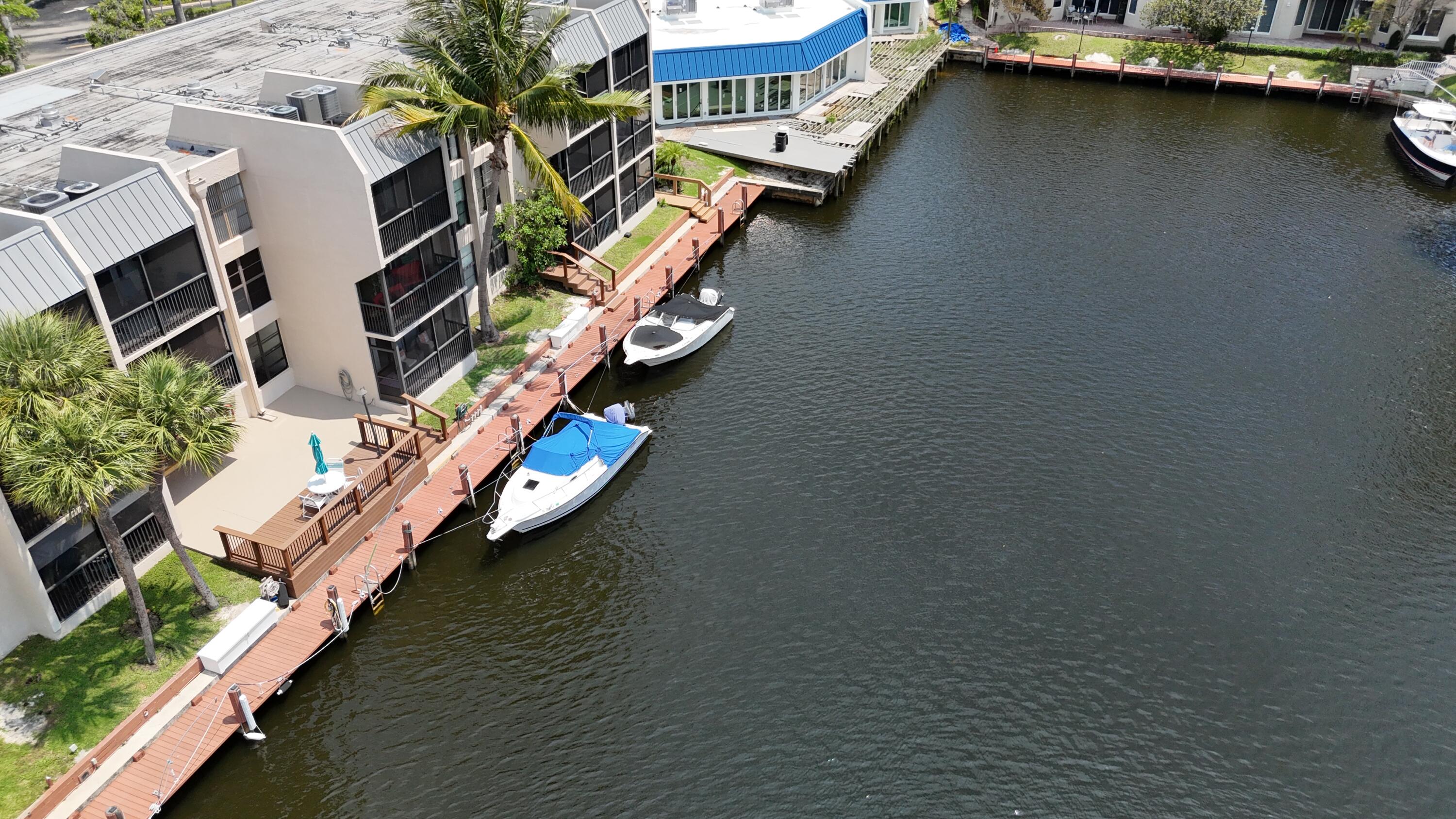 Completely renovated and never lived in, this spectacular first-floor corner waterfront residence offers the ultimate in resort-style living. Everything inside is brand new, featuring a designer kitchen with modern cabinetry, premium finishes, new appliances, new bathrooms, stylish flooring, and a bright open-concept layout. A full-size washer and dryer are conveniently located inside the unit for added convenience. No expense was spared in the remodeling and construction.  This home is further enhanced with complete impact windows and doors, providing peace of mind, energy efficiency, and storm protection.  Step outside your back door to a boat dock and enjoy the tranquil waterfront setting with direct access just steps from your patio. Bring your boat—there is direct ocean access in  approximately twenty minutes. Whether you're relaxing at home or entertaining guests, this property delivers the quintessential South Florida waterfront lifestyle.  The community offers outstanding resort-style amenities, including five swimming pools, a weight room and sauna, pickleball courts, a putting green, a new active clubhouse being built, and beautifully landscaped grounds. Residents also enjoy 24-hour manned roving security, providing added comfort and peace of mind. The maintenance fee includes water, hot water, waste removal, landscaping, cable, and internet, as well as a manned security gate, allowing for truly worry-free living.  Ideally located in Boca Raton, this exceptional home is just minutes from beautiful beaches, shopping, dining, and entertainment. Fort Lauderdale-Hollywood International Airport is approximately 20 minutes away, with Palm Beach International Airport about 25 minutes to the north, making travel exceptionally convenient. Whether you're seeking a full-time residence or a seasonal retreat, this turnkey waterfront gem is ready for you to move in and enjoy.