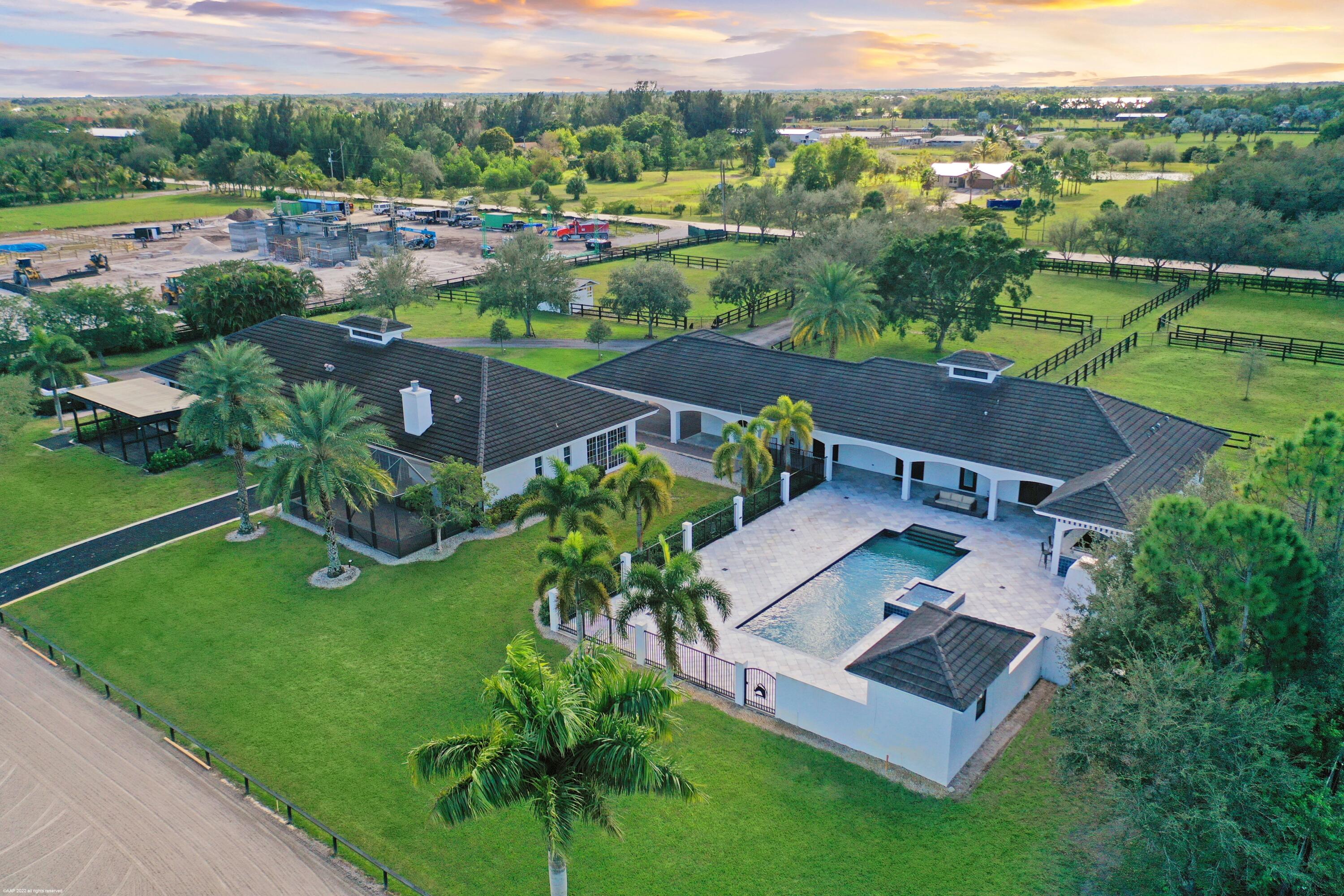 Proudly presenting this opulent 5-acre equestrian estate situated in the sought after equestrian community of Rustic Ranches. Located within the Wellington school system, the home's ideal location is just a short hack from the land bridge bridle path to the horse shows and is near the Wellington environmental preserve & equestrian park. Recently remastered with a stunning modern design, this luxury property boasts two residences and a 6-stall barn with full equestrian amenities. The main house features 3 bedrooms, 3 bathrooms, tons of natural light throughout and spacious living areas; perfect for entertaining and gatherings. The designer interior offers gorgeous wide plank oak floors, an expansive primary suite with sitting area and resort-style en suite and a chef's kitchen with dual... islands, wine cooler, refreshment bar, double ovens, induction cook top and much more. The expansive back terrace will be sure to amaze, featuring a heated salt-water pool, outdoor kitchen, outdoor shower, cabana bathroom access and large gas fireplace. The barn house includes 2 bedrooms, 2 bathrooms, screened-in patio and a wood burning fireplace. The well-designed center aisle main barn is equipped with 6 stalls, feed and tack rooms, full bath, 3 wash racks with hot/cold water, stall cameras, and much more. There are 2 additional stalls with run-outs, round pen, detached equipment building, 6 paddocks, and an oversized arena with mirrors and plenty of room to expand or build a covered ring! Other notable property features include a Koehler generator that runs the entire compound with 1000 gallon propane tank, city water, 3-car covered carport, security cameras around house and barn, extensive landscape lighting, fully fenced perimeter with privacy, and a stately tree-lined gated entrance. 
 
Main House
2,300 sq ft | 3 bed, 3 bath | Built in 2010 | Split floor plan
Resort style salt water swimming pool and spa | Electric and gas heating 
 
Barn House
1,500 sq ft | 2 bed, 2 bath | Wood burning fireplace | Built in 2005
 
Property Features 
Whole-property Koehler generator | 1000 gallon propane tank 
City water
3-car covered carport 26'x40'
Security cameras around house and barn
Extensive landscape lighting
Fully fenced perimeter with privacy 
Automatic Entrance Gates
27'x28' Large detached garage with large doors for equipment, tractor, etc storage
Fully irrigated property from well water

Equestrian Features
6-stall center aisle main barn | Built in 2005 | Feed room | Tack room
Full Bathroom | 3 large outside wash racks with hot & cold water
Roll down barn doors | Functional barn window shutters | Stall surveillance cameras 
Central fly spray system | Fans & water in each stall | Tongue & groove wood ceilings 
2 detached run out stalls
Oversized sand arena | 90' x 240' | Dressage mirrors | Room to expand
6 large paddocks
Round pen