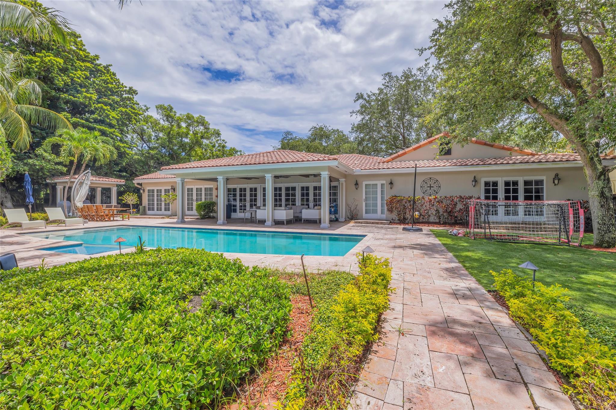 Discover this stunning one-story Ranch style home on North Gordon Isle with 165 ft of waterfront on Lake Stranahan, a 100 ft dock, and ICW access. Set on a 15,320 sq ft lot, the newly renovated home boasts over 3,900 sq ft of custom interiors with vaulted and tray ceilings, hardwood floors, and custom built-ins. The gourmet kitchen is equipped with premium appliances. The home includes a Florida Room, Family Room, and a 5th bedroom used as a den. The master suite offers a luxury bath and two walk-in closets. Enjoy outdoor living with a covered loggia, resort-quality pool, and beautifully landscaped grounds.