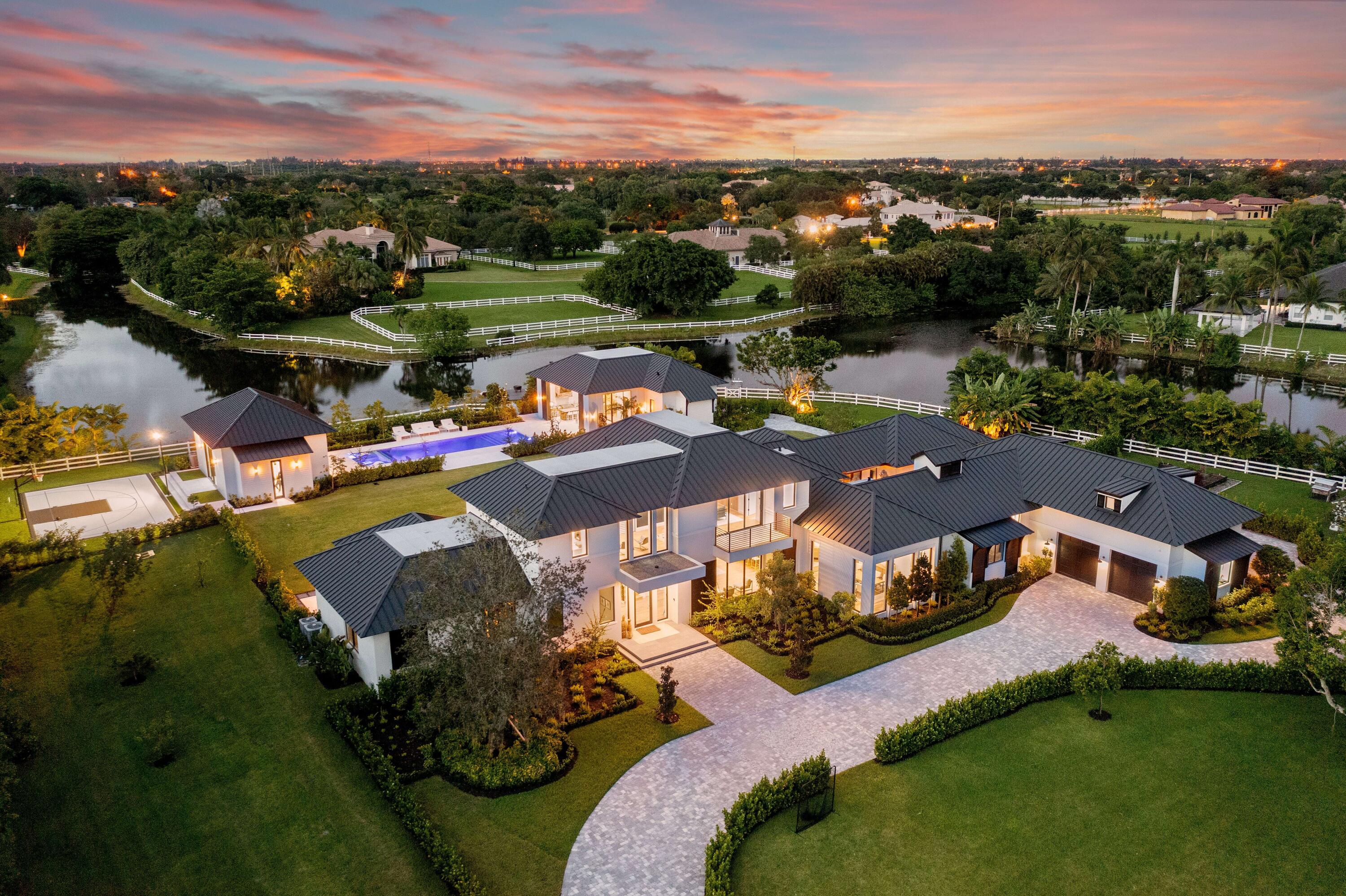 Mi Tierra Delray Beach is an impeccable new contemporary estate offering rich organic design set on nearly 3 acres of idyllic lakefront property. This custom multidimensional compound is situated behind private gates of Tierra Del Rey, an exclusive and sought-after community in Palm Beach County. 
 
The waterfront estate consists of three distinct structures offering the utmost in privacy and modern family lifestyle. It encompasses 10,099 square feet of living space and 12,973 square feet in total. The property features finest materials, craftsmanship and sophisticated organic design and neutral hues. The property features 6 bedrooms, 7 baths, 2 half baths, including main level owner's site with dual baths and closets. An exquisite double-island kitchen and adjacent living area, cast predominantly in brilliant white with light hardwood flooring and similarly toned wood-beam ceiling insets, sets a comfortable chic aesthetic thread that runs throughout many of the rooms. In the case of the chef's kitchen, charcoal cabinetry around the double islands and cooking area (which includes state-of-.the-art appliances) provides a striking contrast to the impressive white silestone quartz countertops. 
 
The open layout possesses an indoor-outdoor flow that seamlessly integrates yet another outdoor entertainment area. This one with a gas fireplace built into a white-brick designer wall that feels like an extension of the family room. Other interior highlights include a media club room with a full wet bar; a cozy theater room; a lush courtyard with a stone firepit, an upstairs den; laundry rooms on first and second floors, and a mammoth playroom. The home is equipped with Crestron Home Automation providing control of audio, video, climate and security.
 
A stone pathway from the lakefront dock leads to a custom-designed pool area bookended by a separate guest house and fitness facility. The one-bedroom, one-bathroom guest house is a sanctuary unto itself. It is complete with a full bedroom, bath, kitchen area, family room and separate waterfront private patio. The rustic outdoor entertainment area is bathed in warm woods, with a summer kitchen, counter seating, a flat-screen TV, and a stone dining table. 
 
The sprawling two-floor main house extends the clean-lined modern aesthetic with country chic accents. Exterior extras, meanwhile, abound. Along with a turf bocce court, a half basketball court made from custom versa-court tiles, the lushly landscaped property provides a variety of outdoor perches (including a terrace off the master bedroom and seating under a row of banyan and fruit trees), 16 x 54 Pool with underwater speakers, a garden area and a fully functional chicken coop.
 
Experience Mi Tierra Delray Beach.