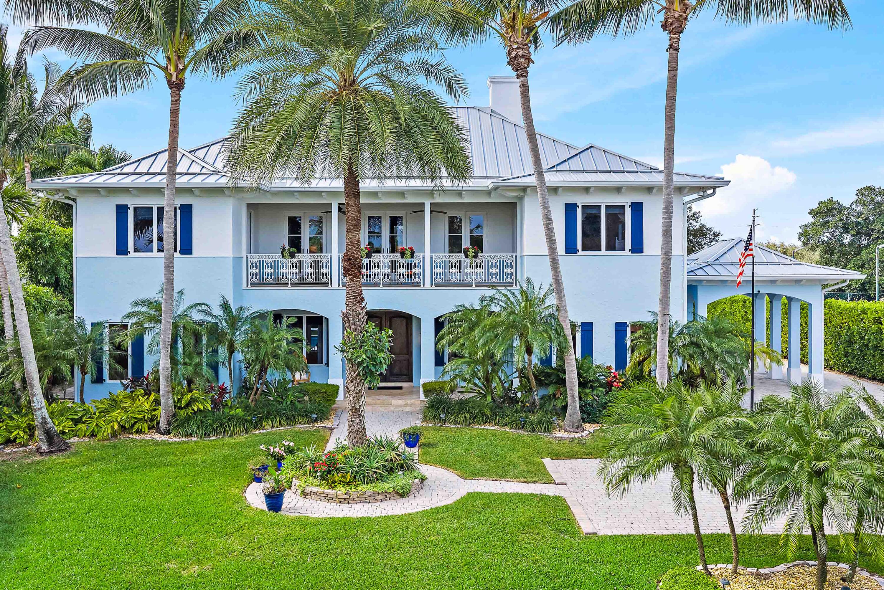 Now attractively repositioned with a recent price improvement, this 4-bedroom, 4.1 bath + two bonus rooms British West Indies-inspired residence captures year-round ocean breezes from its elevated 24- foot position across from the Intracoastal Waterway, set on a generous 3/4 acre lot.  A comprehensive 2022 renovation showcases porcelain flooring, high-end cabinetry, and quartz countertops.  Located in the desirable Indian Hills neighborhood, known for its gentle rolling terrain-an uncommon feature in Southeast Florida-this property is surrounded by a premier enclave, including numerous Intracoastal front estates.  This residence blends coastal flair with fresh, modern touches, enhanced by a whole home generator, new standing seam metal roof (2022) and a 3-car climate controlled garage.    The main level offers a seamless flow between the gourmet kitchen, dining area, butler's pantry and spacious room.  A very private guest suite overlooking the pool provides comfort and separation for visitors, while a media room on the ground floor offers flexible living space. Upstairs, the primary suite is a serene retreat featuring a fireplace, two walk-in closets, a private office, and east- and west-facing balconies for both sunrise and sunset views.  Two additional en suite bedrooms complete the second floor, providing comfort and privacy for guests.  The media room and office offer bonus spaces that may be repurposed to suit a variety of needs.   Outdoors, the resort -style pool and spa (2022) feature a saltwater filtration system and are surrounded by palms and a privacy hedge, creating a tranquil and private setting. A covered lanai provides shaded outdoor living. Plans are available to accommodate a future elevator should the need arise, offering flexibility for long-term living.  Indian Hills offers Intracoastal access and is directly across from Jupiter Hills Golf Club, and just a short drive to other world class golf destinations including The Medalist, McArthur, Apogee and Atlantic Fields.  Also, near the pristine beaches of Jupiter Island, as well as fine dining and upscale shopping-and only 30 minutes from both PBI and Witham Field. This home combines elegance, privacy and an unbeatable location-Florida living at its finest!