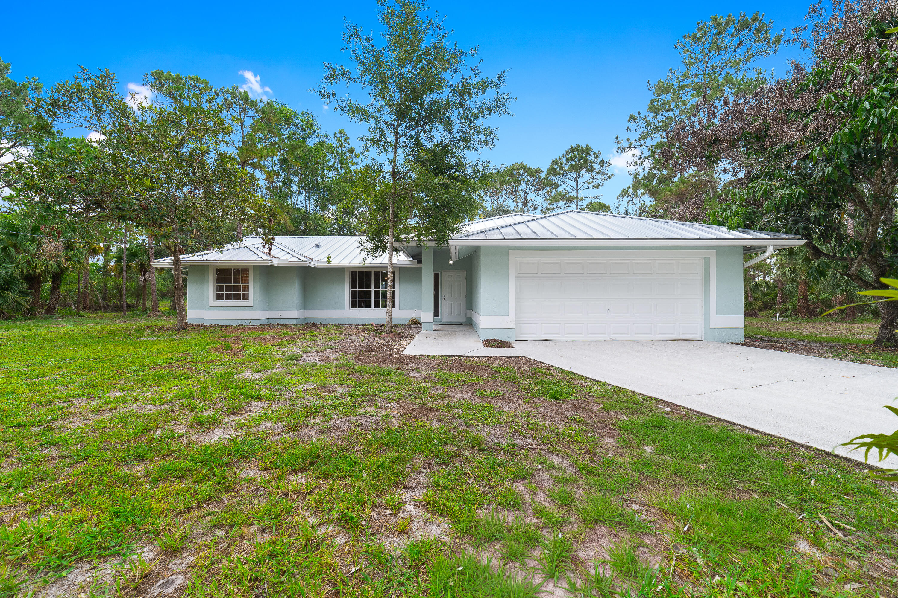 Welcome to this charming 3-bedroom, 2-bathroom single-family home located in the peaceful, rural setting of The Acreage subdivision—with no HOA! This inviting property boasts a brand-new 2024 standing-seam metal roof and a hybrid water heater from 2023. Inside, you will find durable luxury vinyl plank flooring throughout the bedrooms and classic tile in the kitchen and formal living areas. The customized kitchen comes equipped with beautiful soft-close hardware and sturdy dovetail cabinetry. Outdoor enthusiasts will love being close to the Grassy Waters Preserve, J.W. Corbett Wildlife Management Area, and Acreage Community Park's recreation fields.  Plus, major commuter routes like Northlake Boulevard are just minutes away, offering effortless travel to shopping and dining. All measurements are approximate. Take a look at the 3D virtual walk-through.